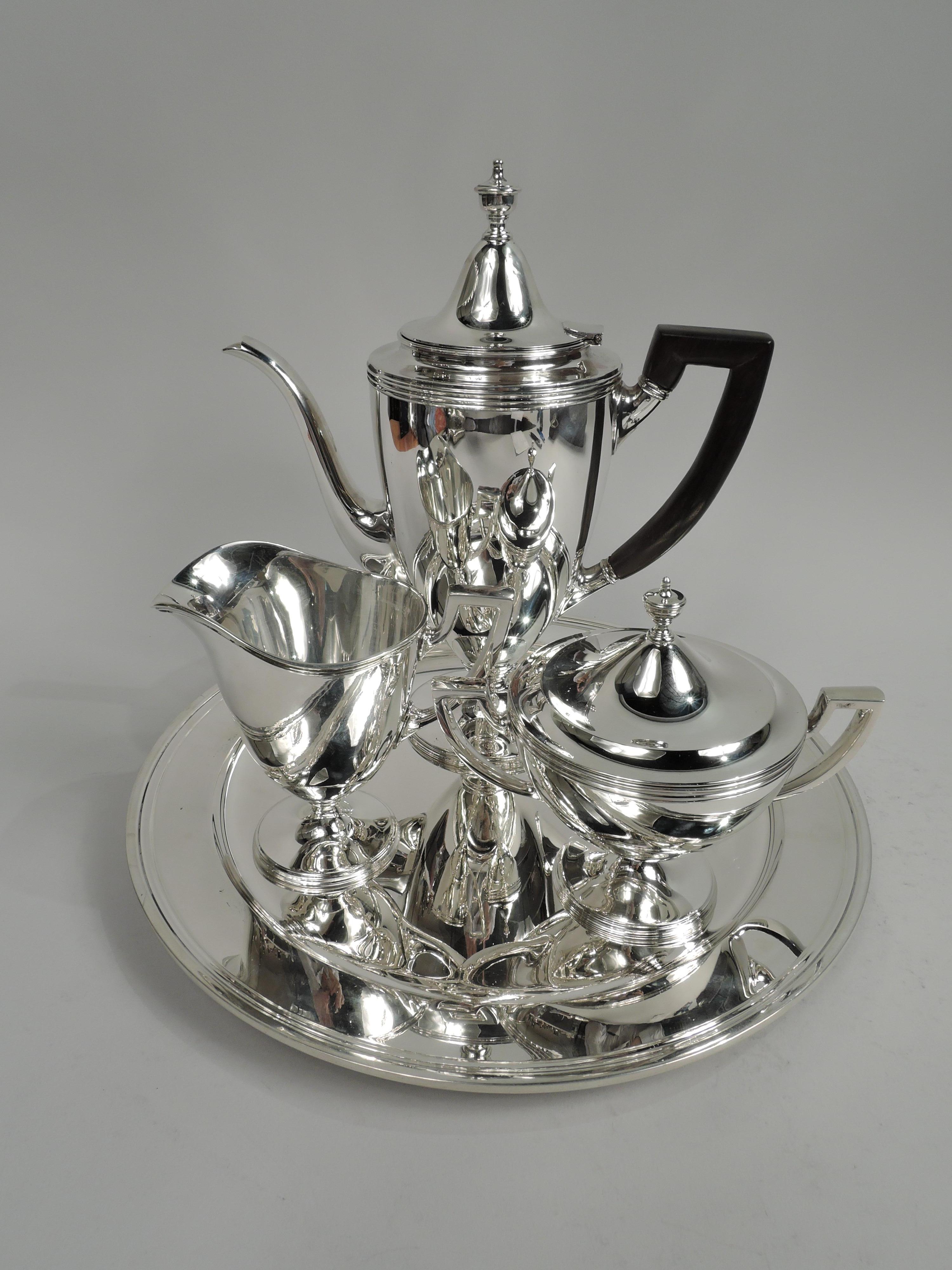 American Classical sterling silver 3-piece coffee set. Made by Tiffany & Co. in New York. Each: Curved and tapering body on stepped and raised foot. Handles scroll bracket; coffeepot handle stained wood. Covers domed with vasiform finial. Coffeepot