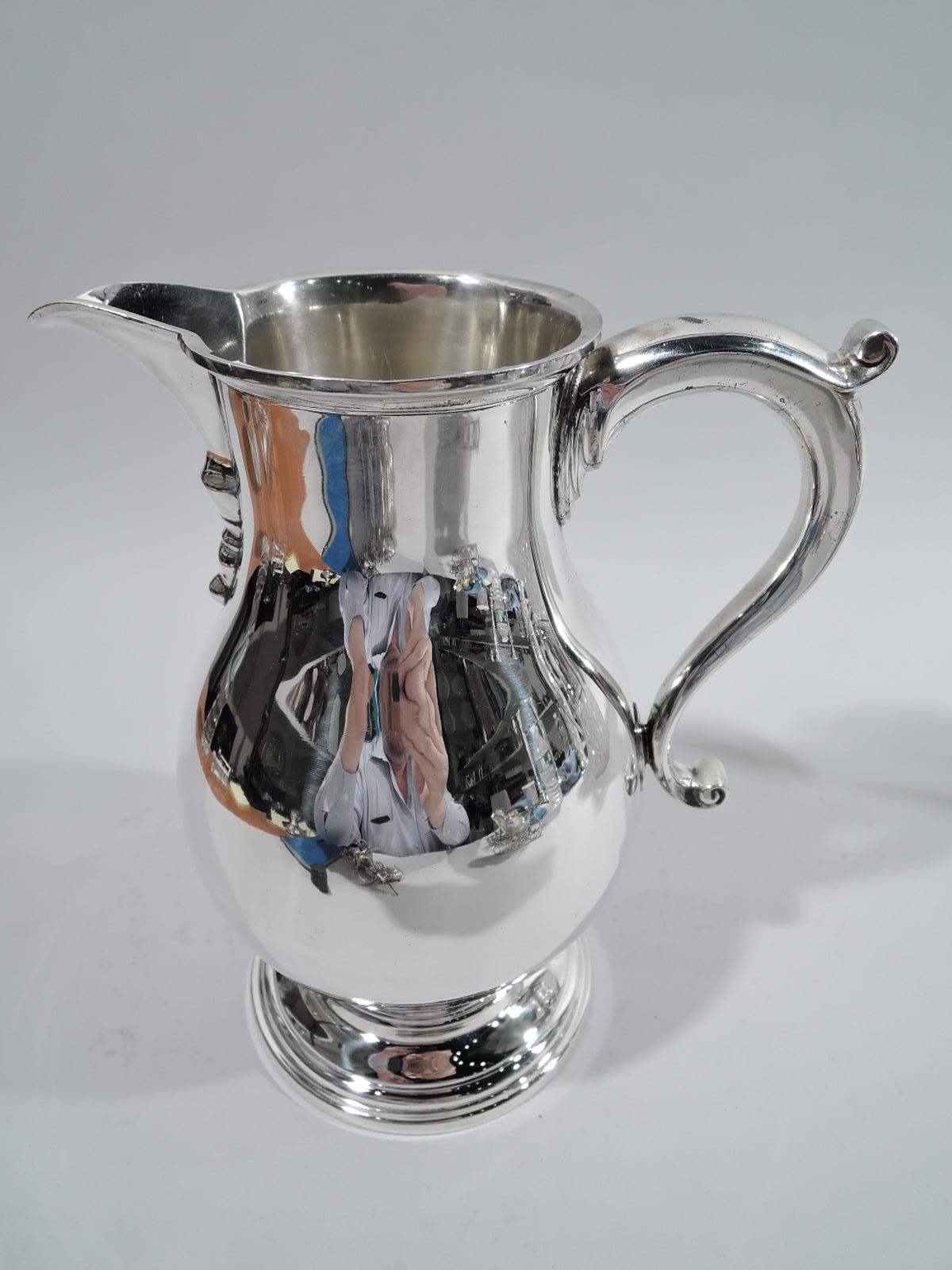 American Colonial-style sterling silver water pitcher, ca 1920. Retailed by Tiffany & Co. in New York. Baluster body with capped scroll handle and v-spout with base ornament, and stepped and round foot. Holds 2 3/4 pints. Marked “Tiffany & Co. /