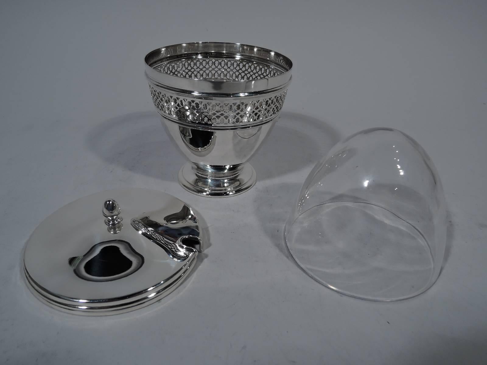 Edwardian sterling silver jam pot. Made by Tiffany & Co. in New York, circa 1913. Curved sides and raised foot. Band of pierced scrollwork near rim. Cover gently raised with acorn finial. Clear glass liner. Hallmark includes pattern no. 18423 (first