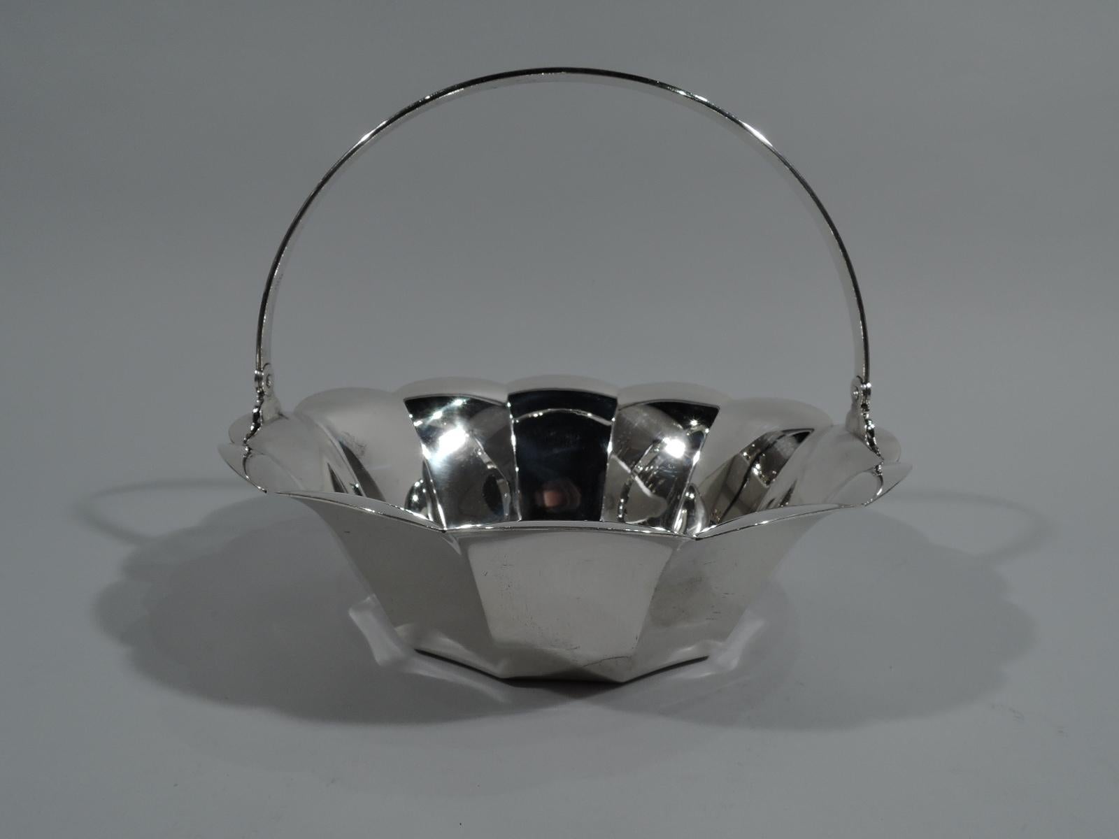 Cesta de plata de ley moderna de mediados de siglo. Fabricado por Tiffany & Co. en Nueva York. Circular con lados estriados y borde acampanado y festoneado. Empuñadura oscilante en forma de C. Hallmark incluye el patrón n.º 23076 y la letra L de