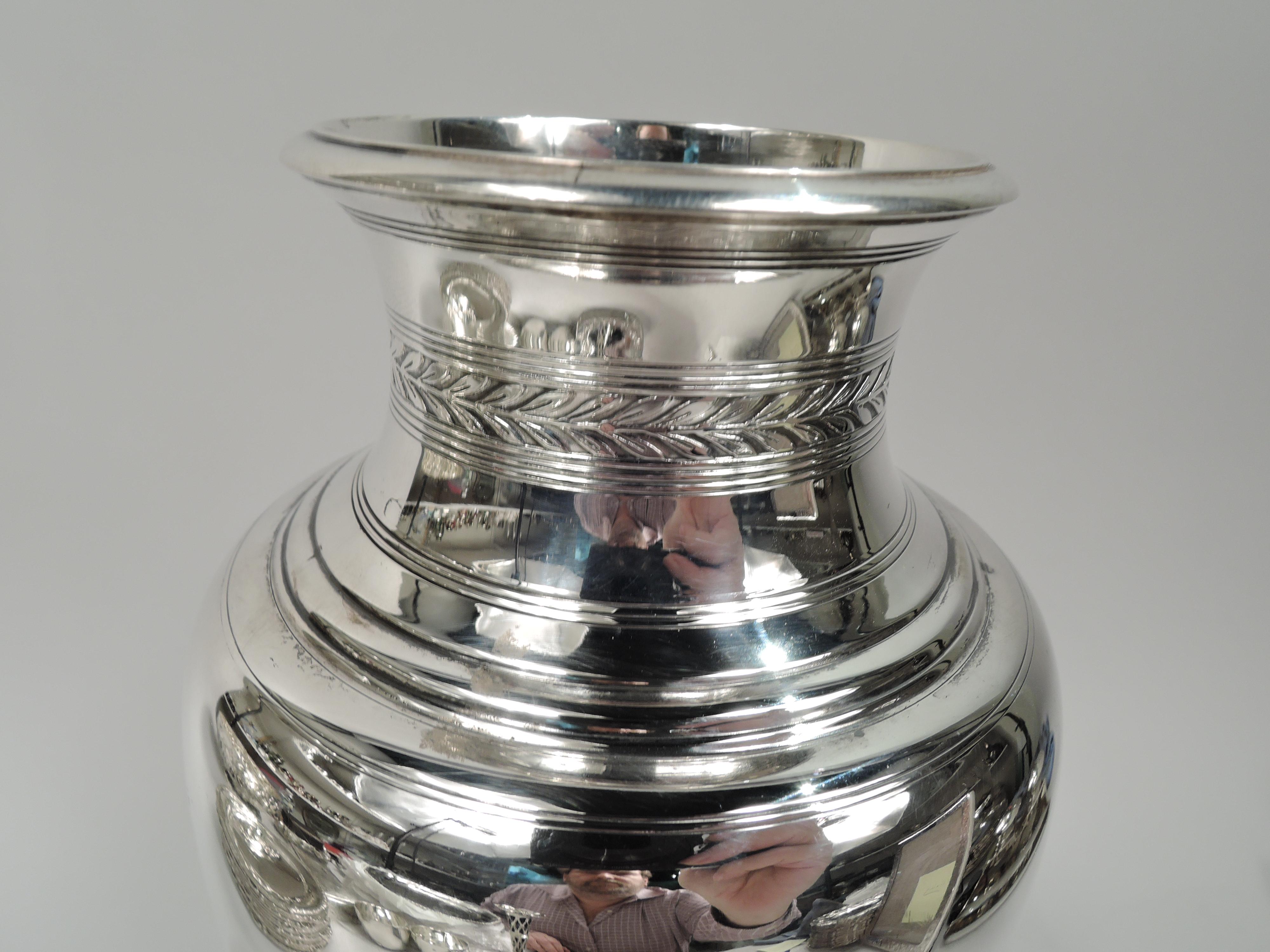 Modern Classical sterling silver vase. Made by Tiffany & Co. in New York, ca 1913. Ovoid body with short inset neck and raised foot. Engraved and acid-etched stylized ornament: Imbricated leaf border on neck and egg-and-dart border on foot.