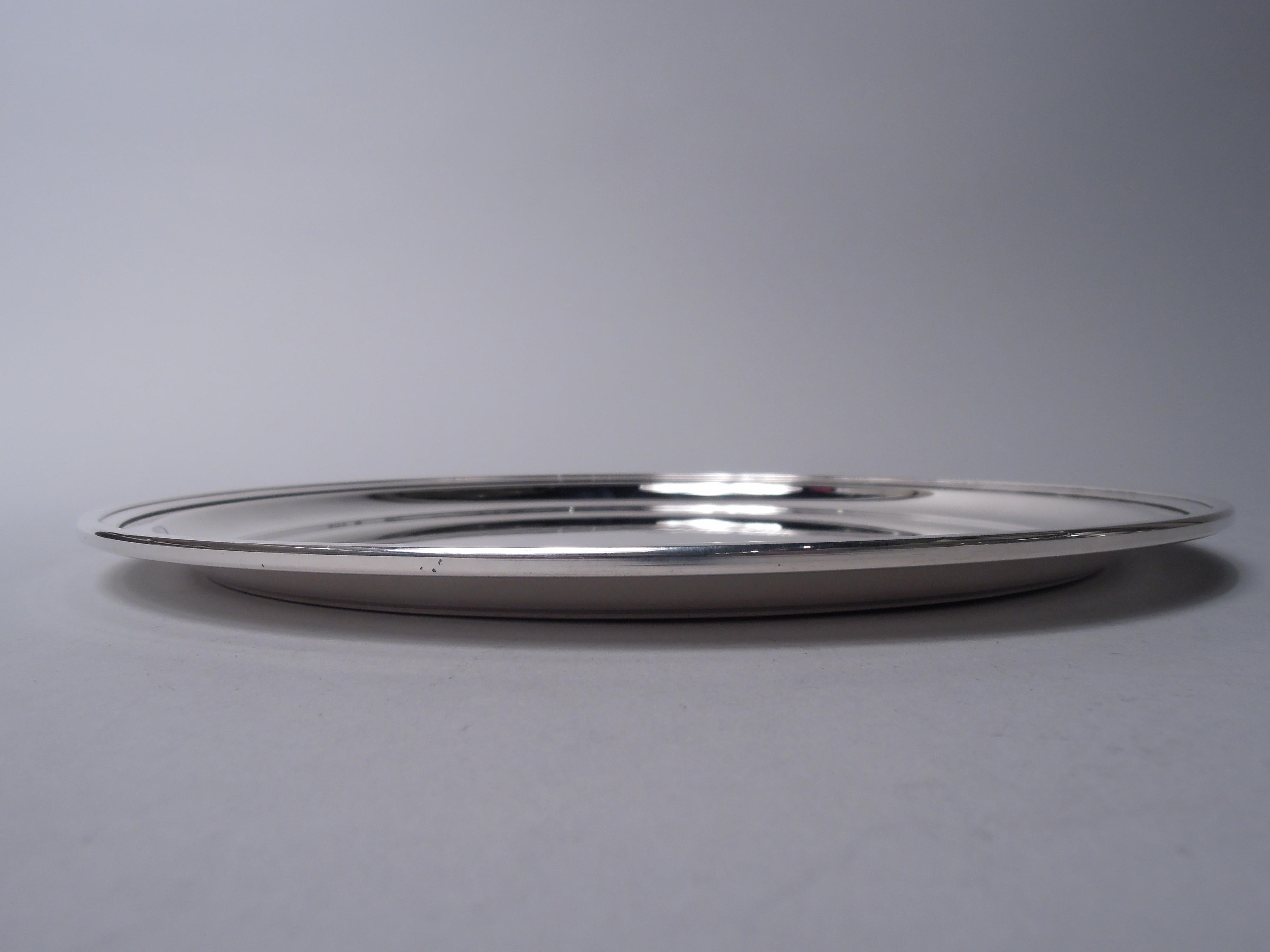 Plateau de service moderne en argent sterling. Fabriqué par Tiffany & Co. à New York, ca. 1960. Rond avec un bord en escalier. Intelligent et fonctionnel. Un bon poids. Entièrement marquée avec le cachet du fabricant et le numéro de modèle 21252.