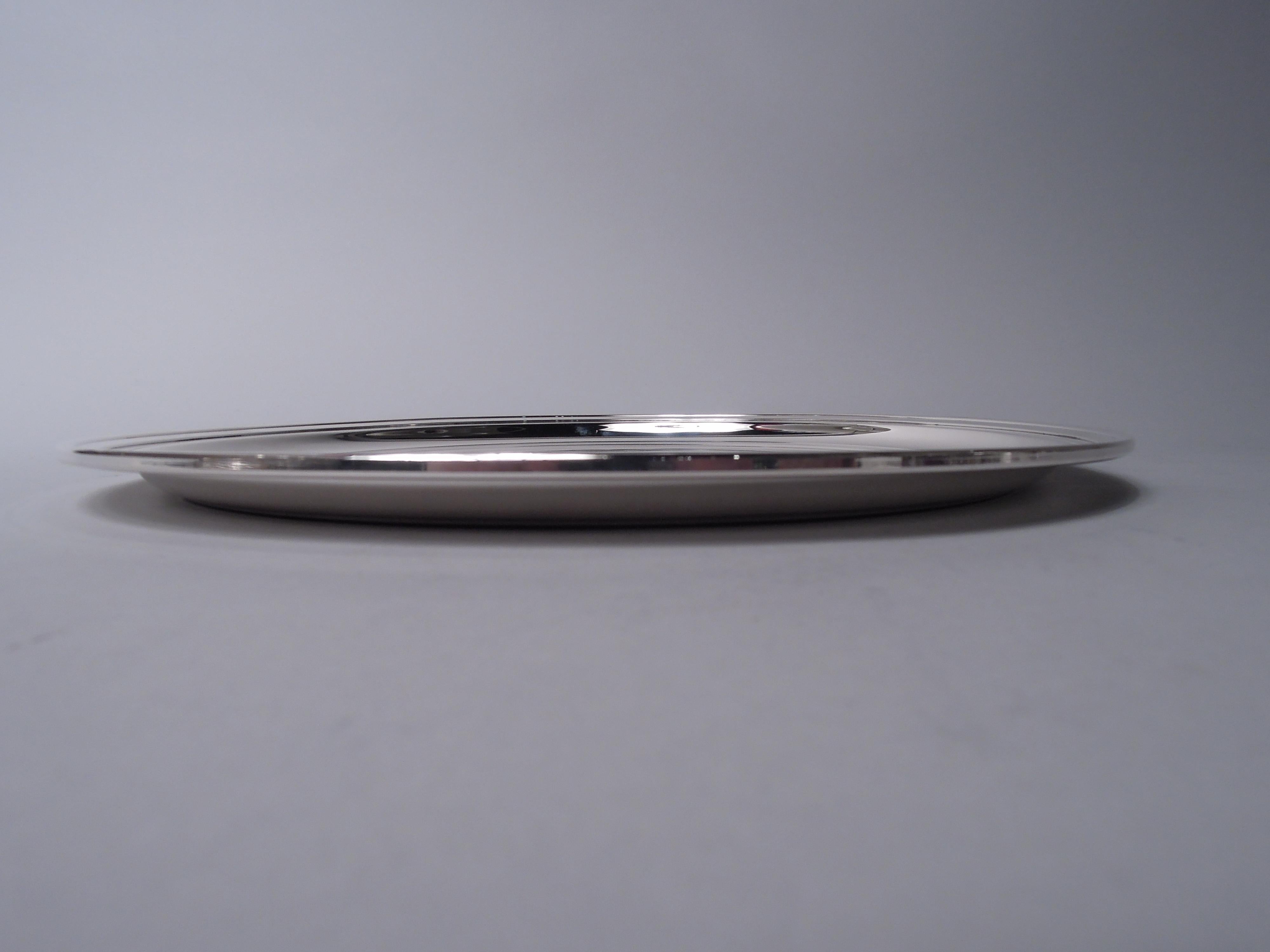 Plateau moderne en argent sterling. Fabriqué par Tiffany & Co. à New York, ca. 1960. Rond avec un bord en escalier. Entièrement marquée avec le cachet du fabricant et le numéro de modèle 21253. Poids : 19 onces troy. 