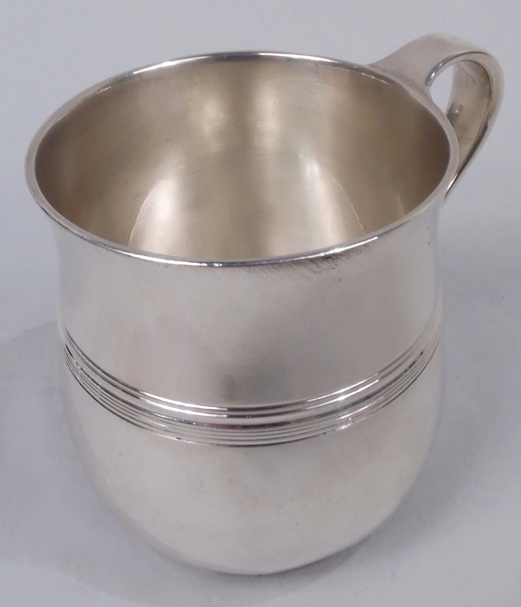 Modern sterling silver baby cup. Made by Tiffany & Co. in New York, ca 1928. Curved bowl with flared mouth rim, high-looping handle, and foot ring; reeded band. Plenty of room for engraving. Fully marked including maker’s stamp, pattern no. 21213