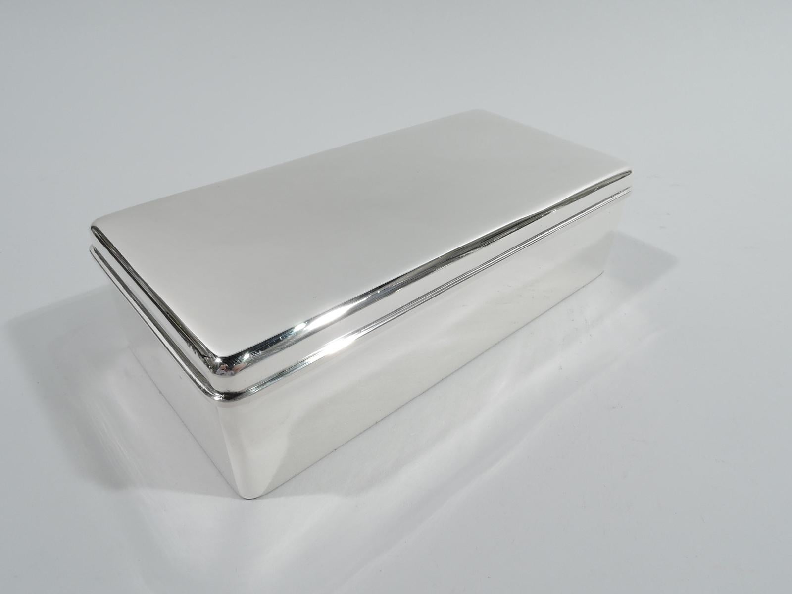 Modern sterling silver box. Made by Tiffany & Co. in New York, ca 1927. Rectangular with straight sides and curved corners. Cover flat, raised, and hinged with molded rim. Box interior cedar lined. Cover interior gilt. Fully marked including maker’s