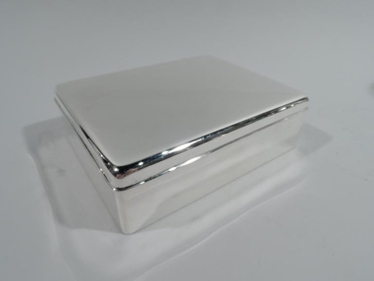 Modern sterling silver box. Made by Tiffany & Co. in New York, ca 1930. Rectangular with straight sides and curved corners. Cover flat and hinged with molded rim. Box interior cedar lined and partitioned. Cover interior gilt. Fully marked including