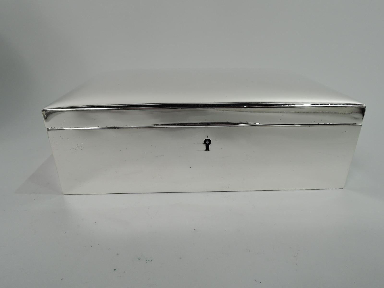 Modern sterling silver keepsake jewelry box, ca 1920. Retailed by Tiffany & Co. in New York. Rectangular with straight sides. Cover hinged with gently curved top and tapering tab. Box and cover interior velvet lined. With key. Marked “Tiffany & Co.