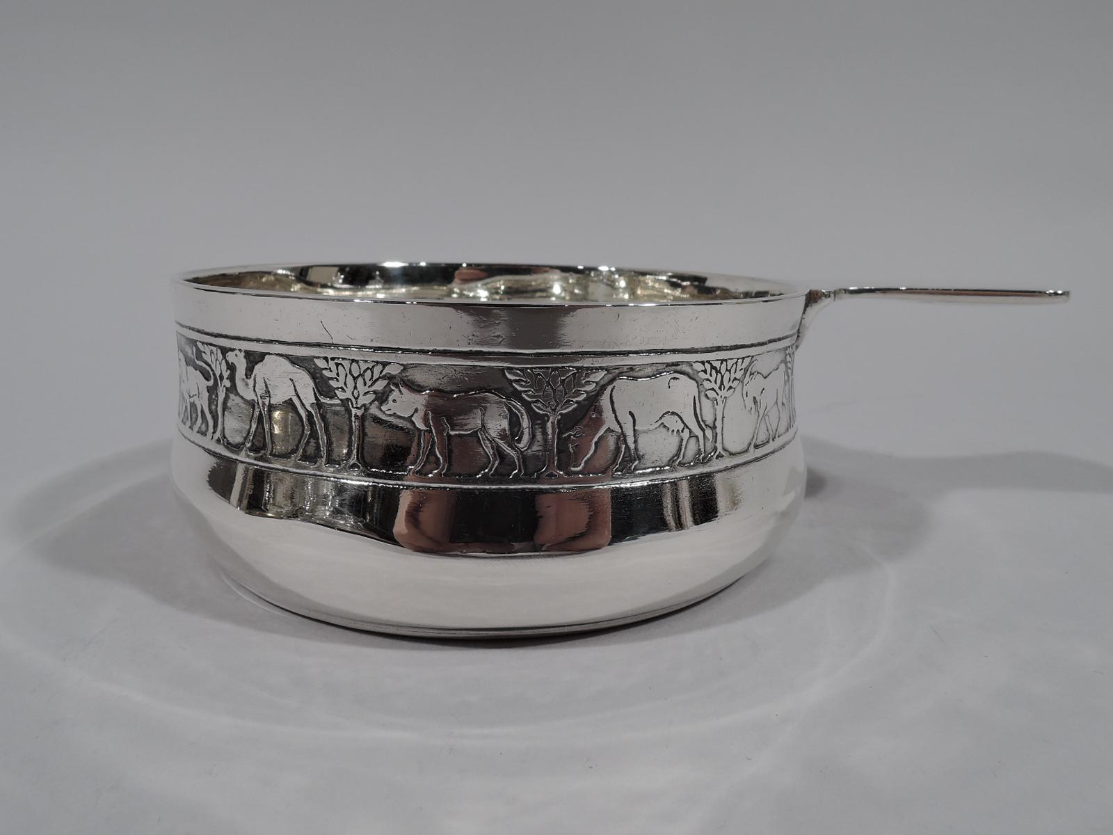 Modern sterling silver porringer with Noah’s Ark motif. Made by Tiffany & Co. in New York, circa 1926. Gently curved sides and solid shaped handle. On exterior is acid-etched frieze with a lion, camel, elephant, bear—and so on single file through