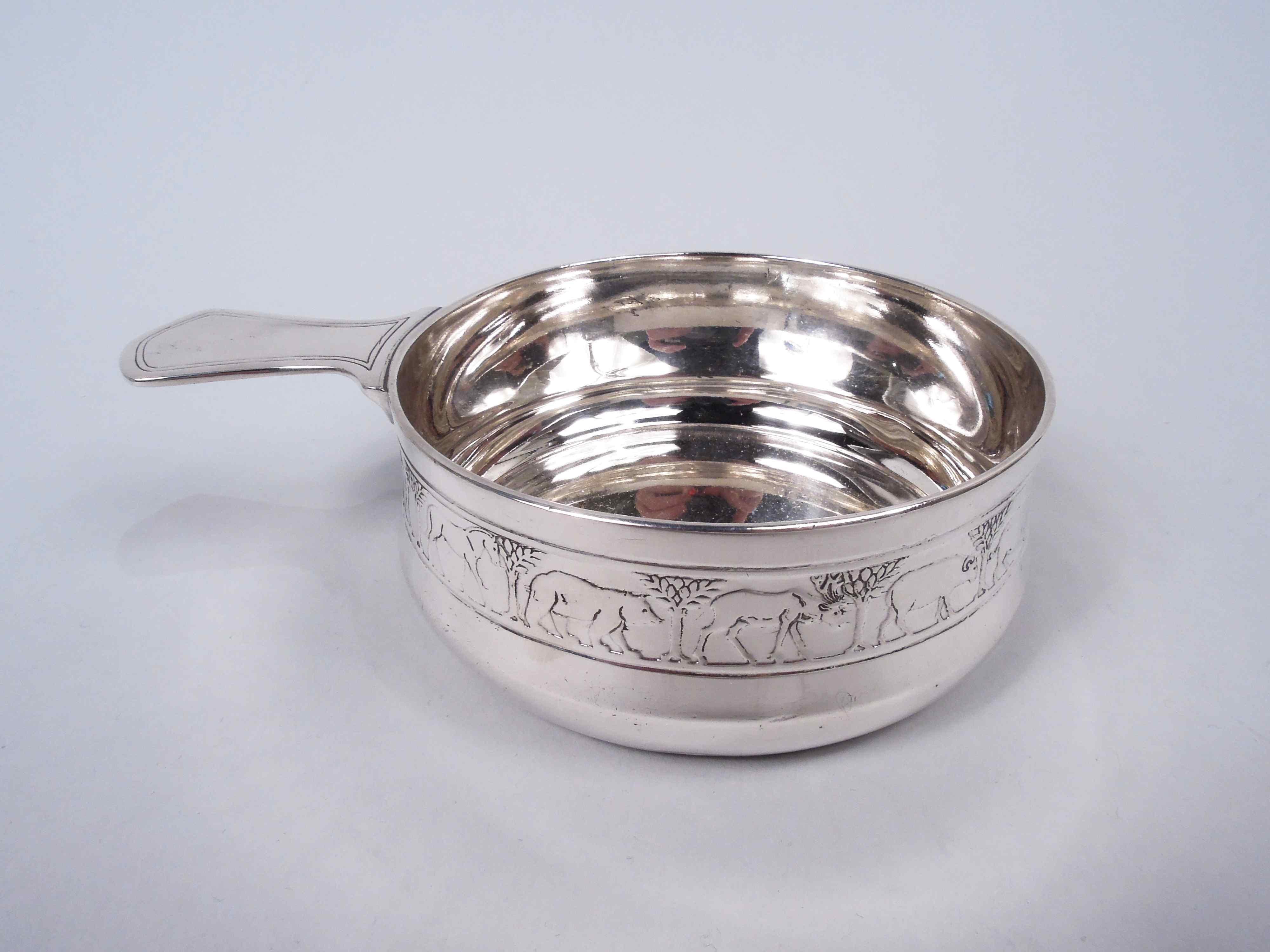Modern sterling silver porringer with Noah’s Ark motif. Made by Tiffany & Co. in New York, ca 1926. Bellied bowl and solid shaped handle. On exterior is acid-etched frieze with a lion, camel, elephant, bear—and so on single file through the animal