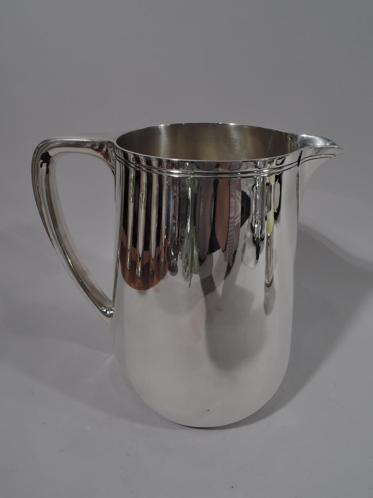 Modern sterling silver water pitcher. Made by Tiffany & Co. in New York. Upward tapering sides, scrolled bracket handle, and v-spout. Spare incised banding near rim. Holds 3 1/2 pints. Fully marked including pattern no. 22343, director’s letter M