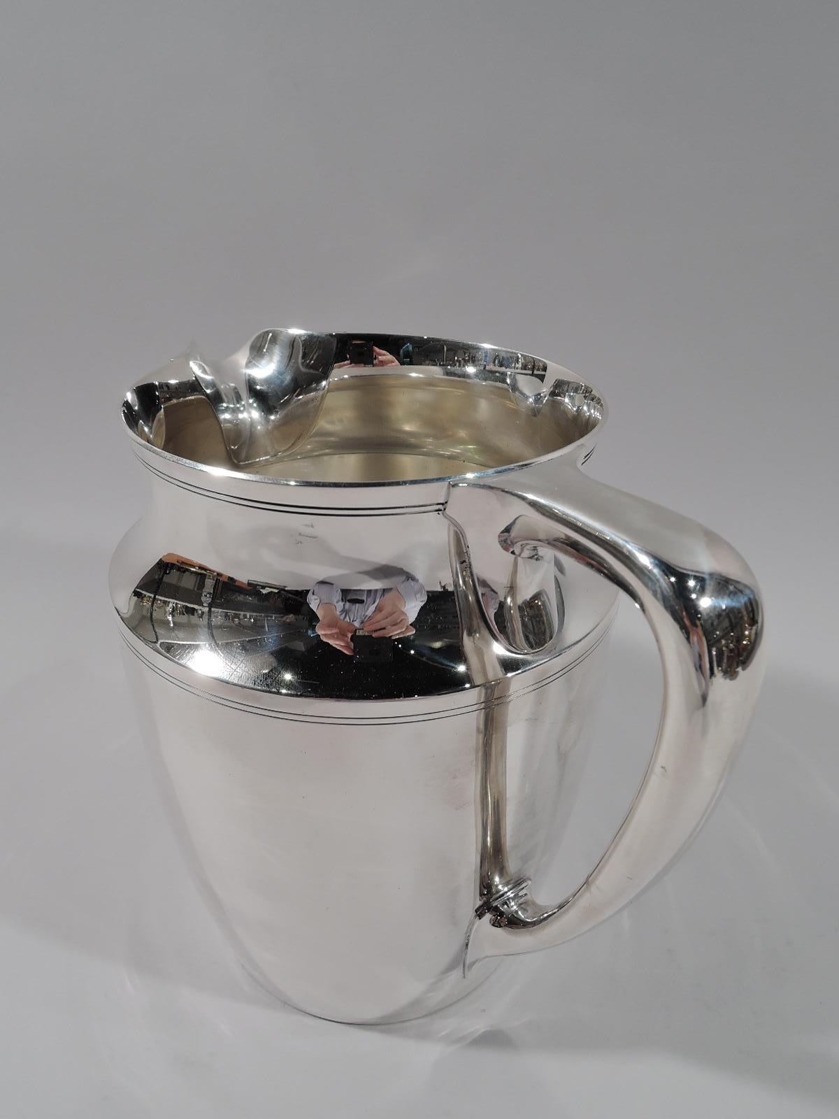 Modern sterling silver water pitcher. Made by Tiffany & Co. in New York. Gently curved and tapering sides, concave neck, and scroll bracket handle. Double linear bands incised at rim, shoulder, and base. Fully marked including pattern no. 20211,