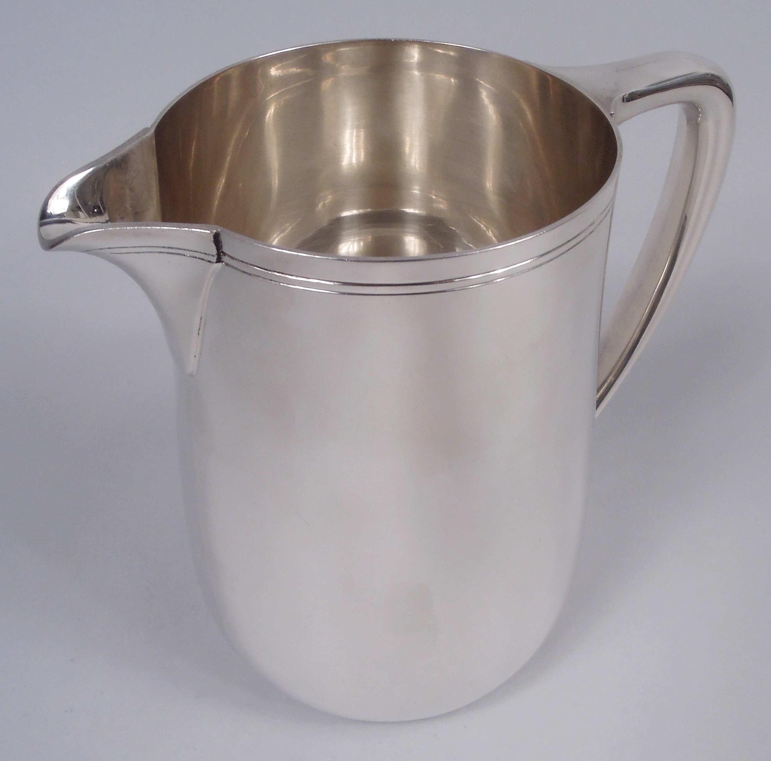 Modern sterling silver water pitcher. Made by Tiffany & Co. in New York. Upward tapering sides, scrolled bracket handle, and v-spout. Spare incised banding near rim. Holds 3 1/2 pints. Fully marked including maker’s stamp, pattern no. 22343, and