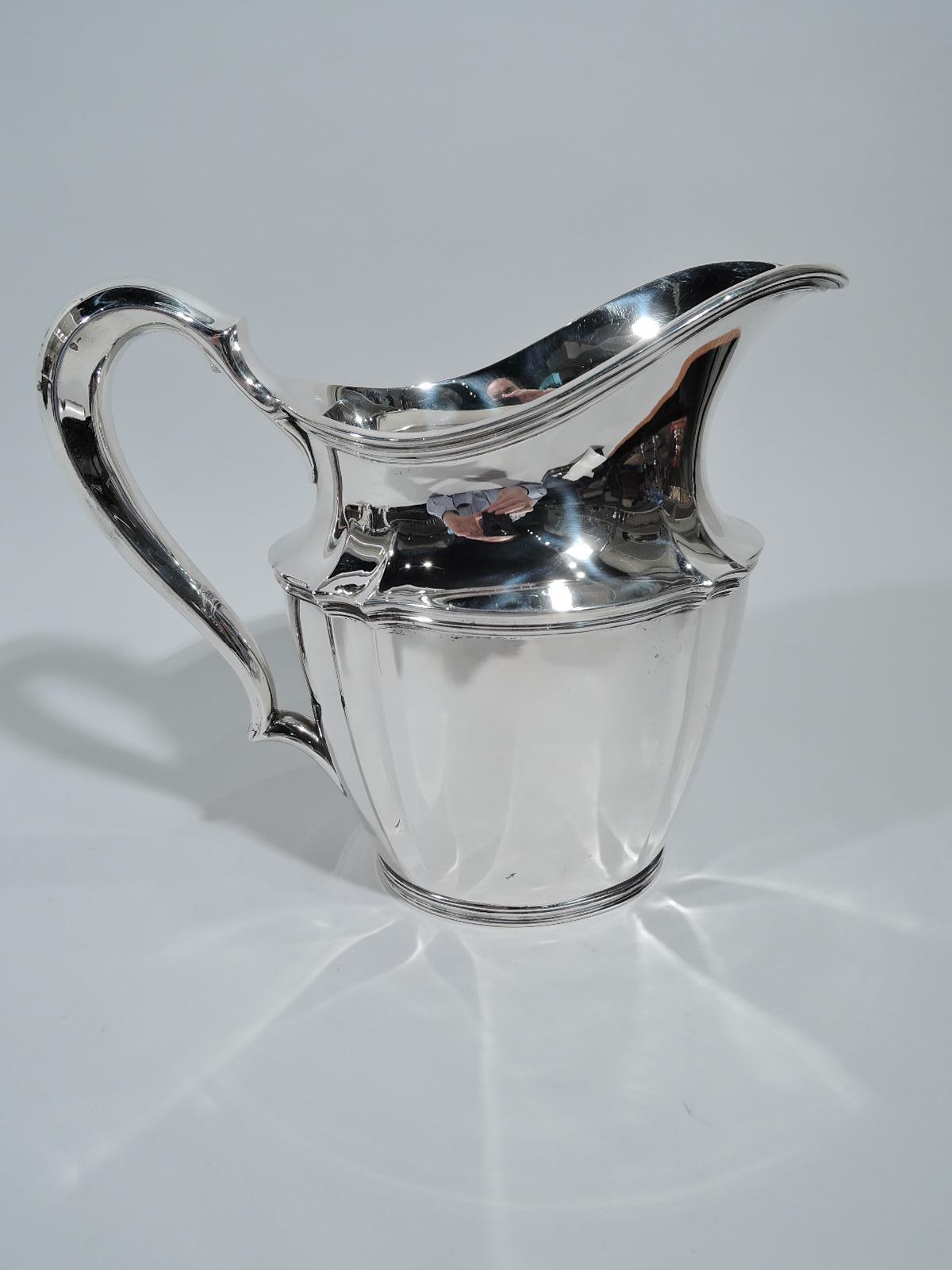 Traditional sterling silver water pitcher. Made by Tiffany & Co. in New York, circa 1910. Tapering oval body, helmet mouth, and high-looping handle. Fluting and reeding. Fully marked including pattern no. 14997D, director’s letter m, and volume (3