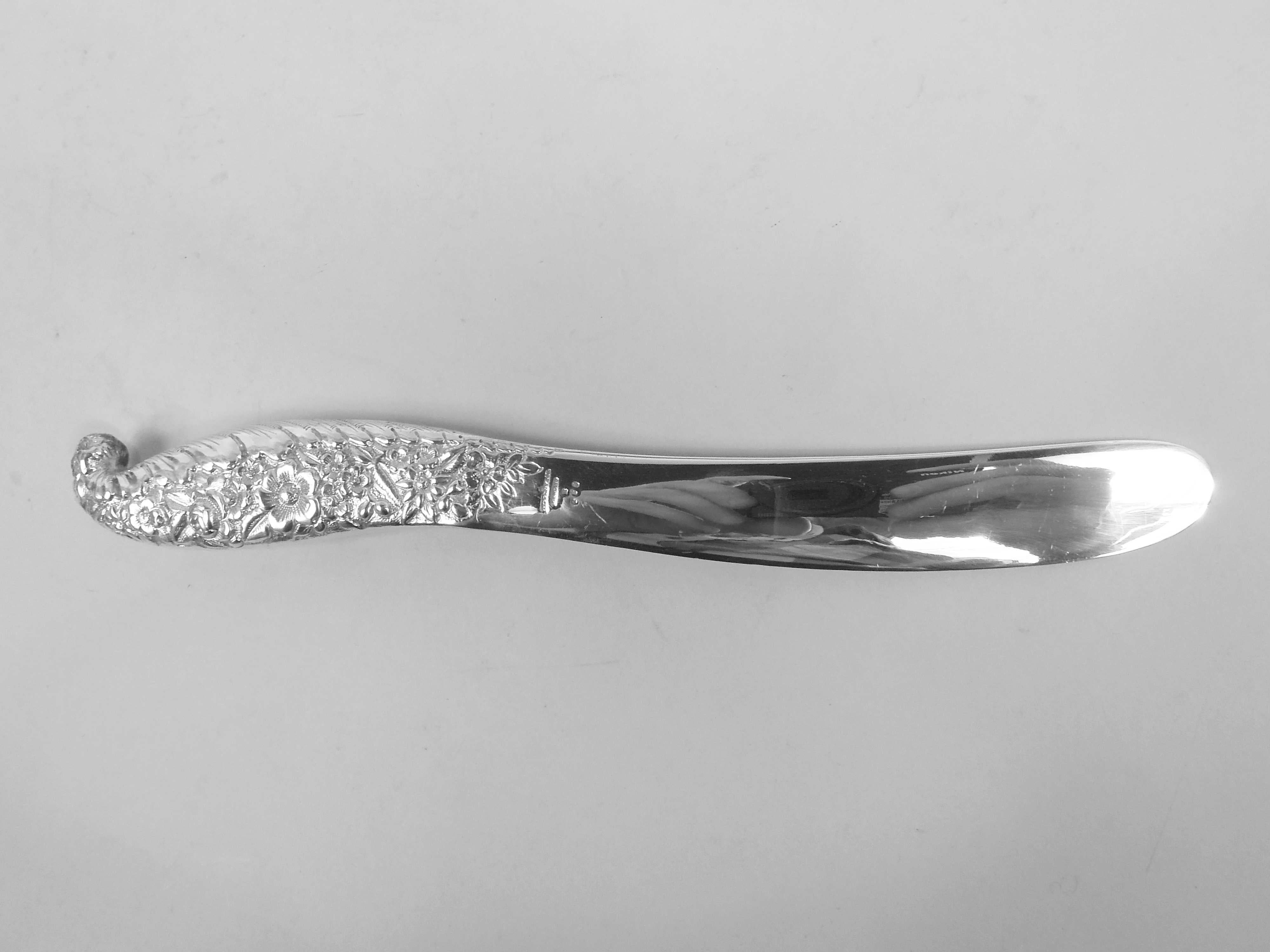 Victorian Classical sterling silver paper knife. Made by Tiffany & Co. in New York, ca 1885. Serpentine and integral with hollow handle tapering into flat blade. Handle has allover floral repousse with feathered leaf border at bottom. Blade recto