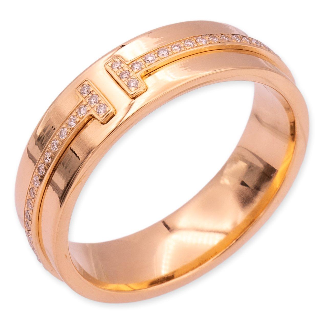 Tiffany & Co. wide band ring from the T collection finely crafted in 18 karat rose gold featuring an overlapping T motif thin band set with round brilliant cut diamonds weighing 0.12 carats. Ring measures 5.5 mm wide. Fully hallmarked with logo and