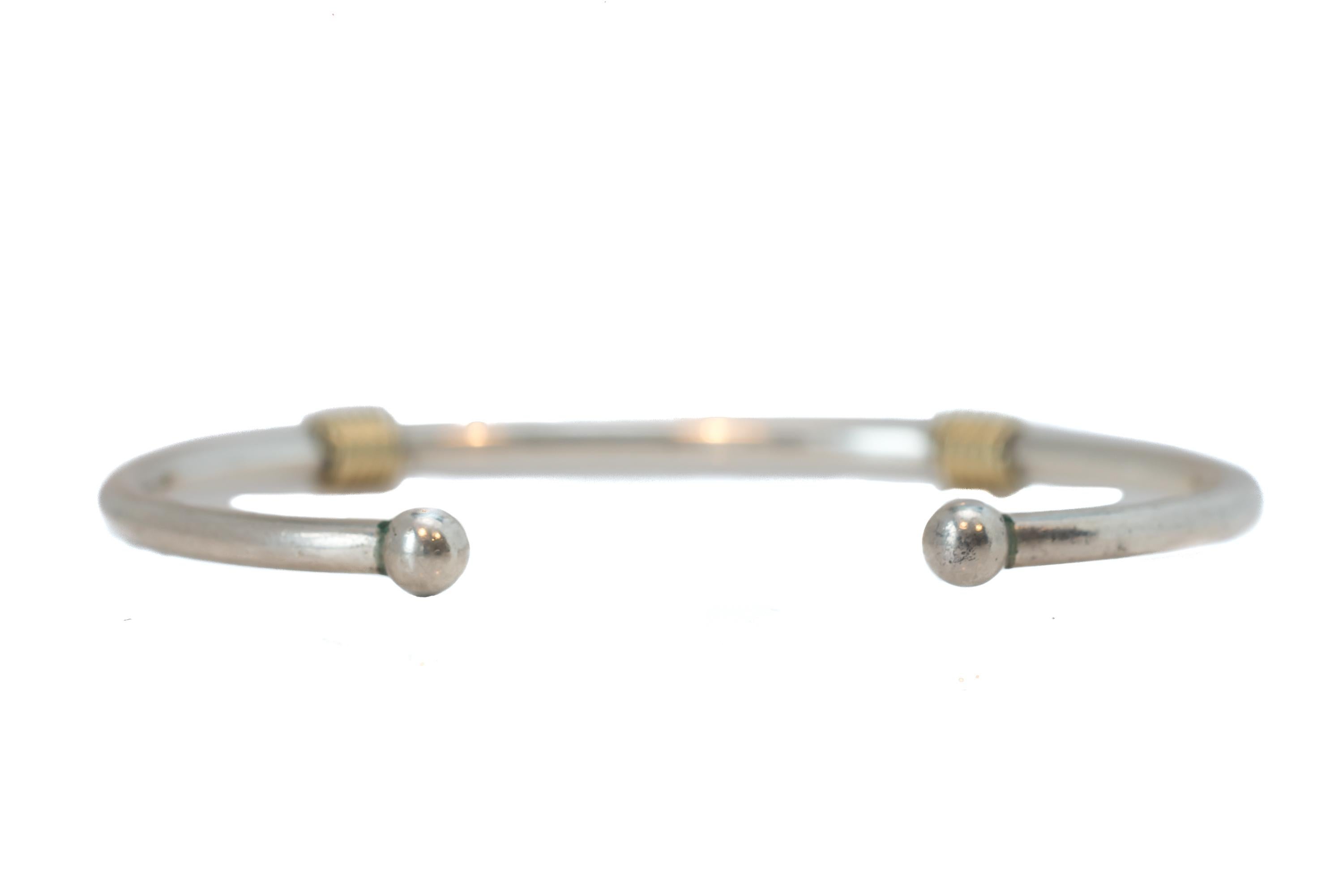 Tiffany and Co. Sleek Design Bangle Bracelet
Torc Style design featuring a High Polish Sterling Silver and 18 Karat Yellow Gold Wire Wrap Accents

Bracelet is signed along the inner surface

Bracelet Details:
Size: 6 inches from end to end, 1 inch