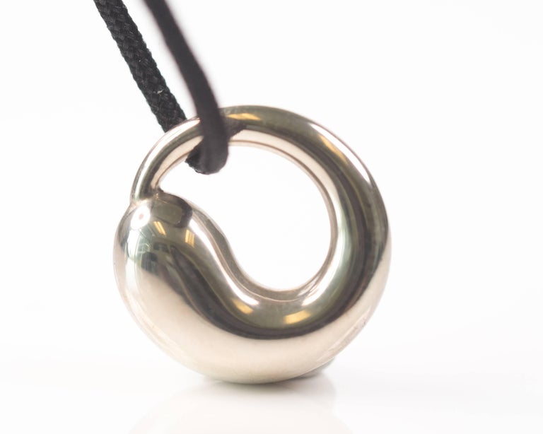 Elsa Peretti for Tiffany and Co. Eternal Circle Pendant Necklace - Sterling Silver

Features a Sterling Silver Eternal Circle floating on a black satin cord. This gorgeous pendant exemplifies Elsa Peretti's signature organic style. The circle flows