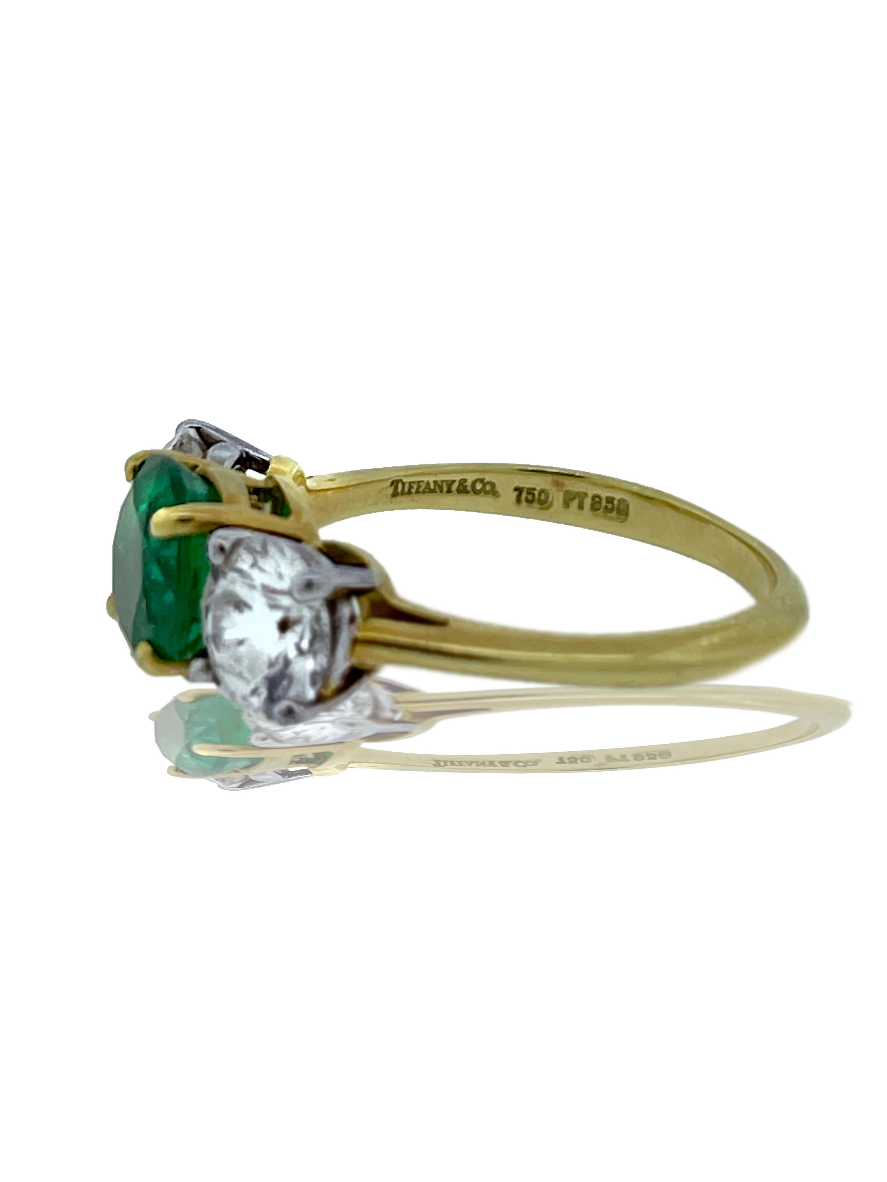 Ein klassischer Smaragd- und Diamantring von Tiffany and Co. ist in diesem Dreisteinring zu sehen. Der Mittelstein ist ein kolumbianischer, runder Smaragd mit Schliff.  Einen natürlichen Smaragd in dieser Größe und mit diesem Schliff zu finden, ist
