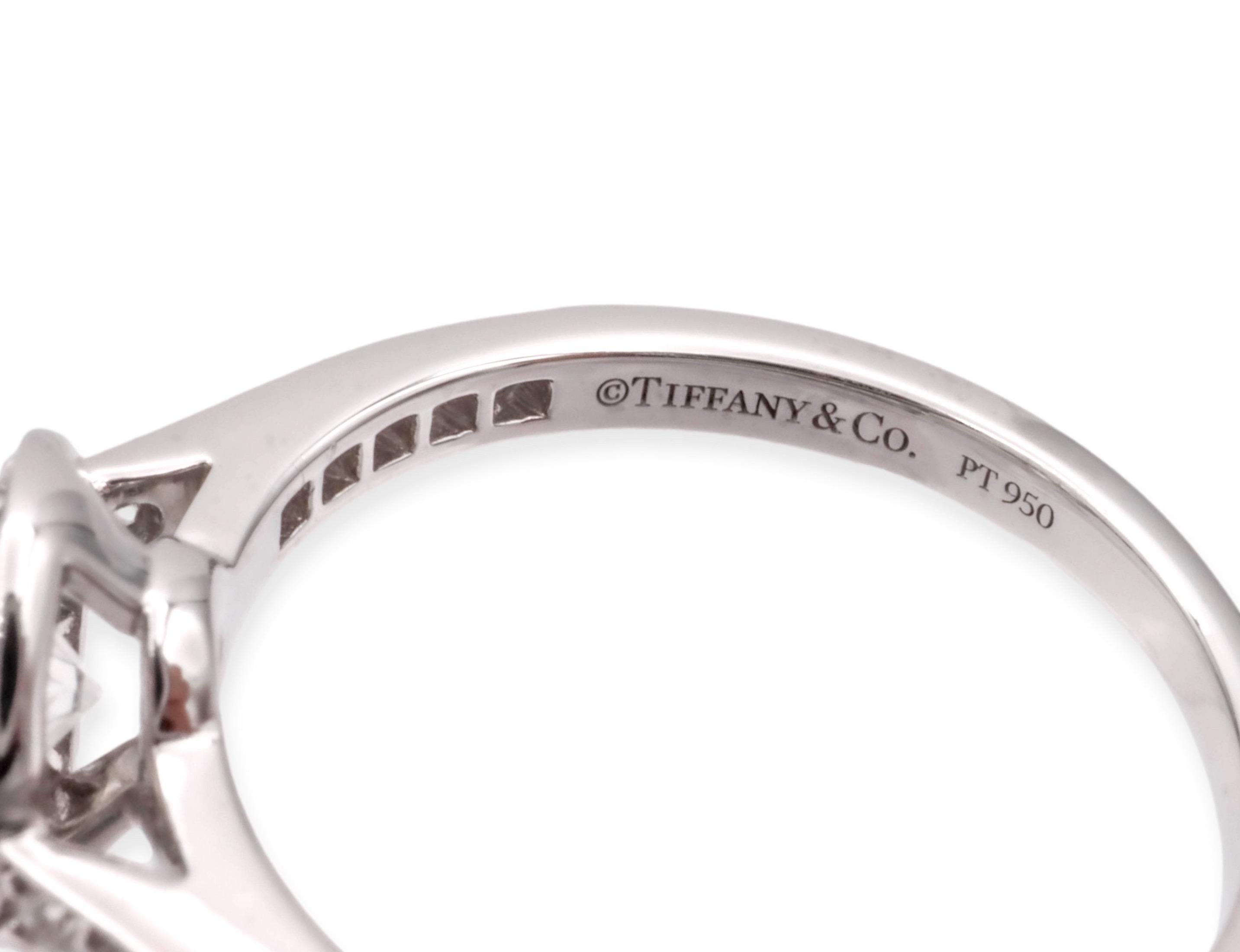 Tiffany & Co. engagement ring from the Embrace collection finely crafted in platinum featuring a round brilliant cut center diamond set in a bezel weighing .50 carats surrounded by a halo of channel set round brilliant cut diamonds and going down