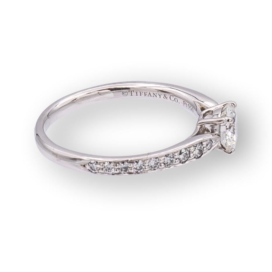 Tiffany and Co. diamond engagement ring from the Harmony collection finely crafted in Platinum featuring a round brilliant 0.45 ct center G color , VS1 clarity graded by The Gemological Institute of America. The ring design tapers in to the center