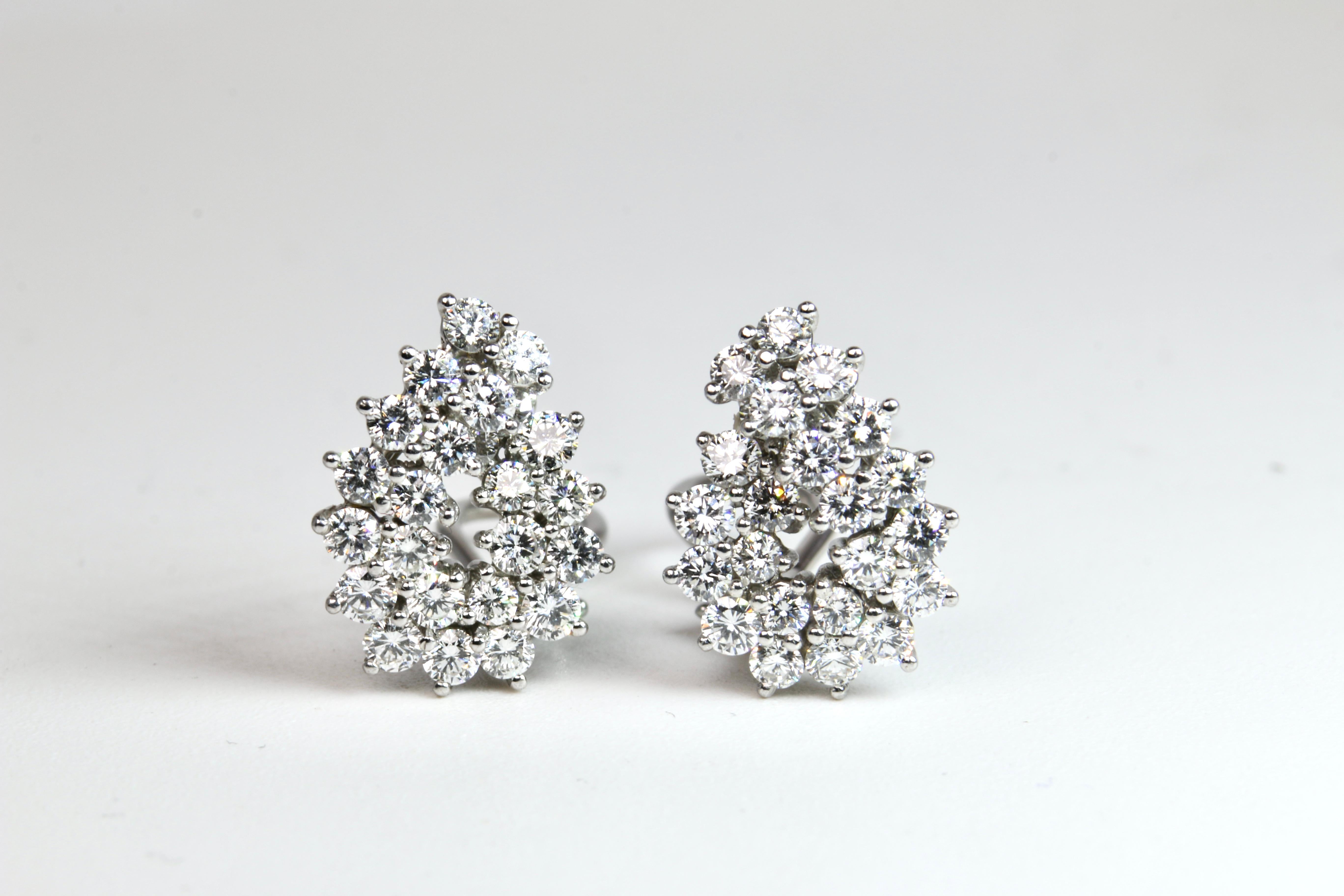Tiffany & Co Platinum Diamond Earrings have a double row swirl pattern prong set with a total of 4.16 carats of bright round brilliant cut diamonds. Earrings feature an Omega style clip on each with pad area for security. These clip style are easily