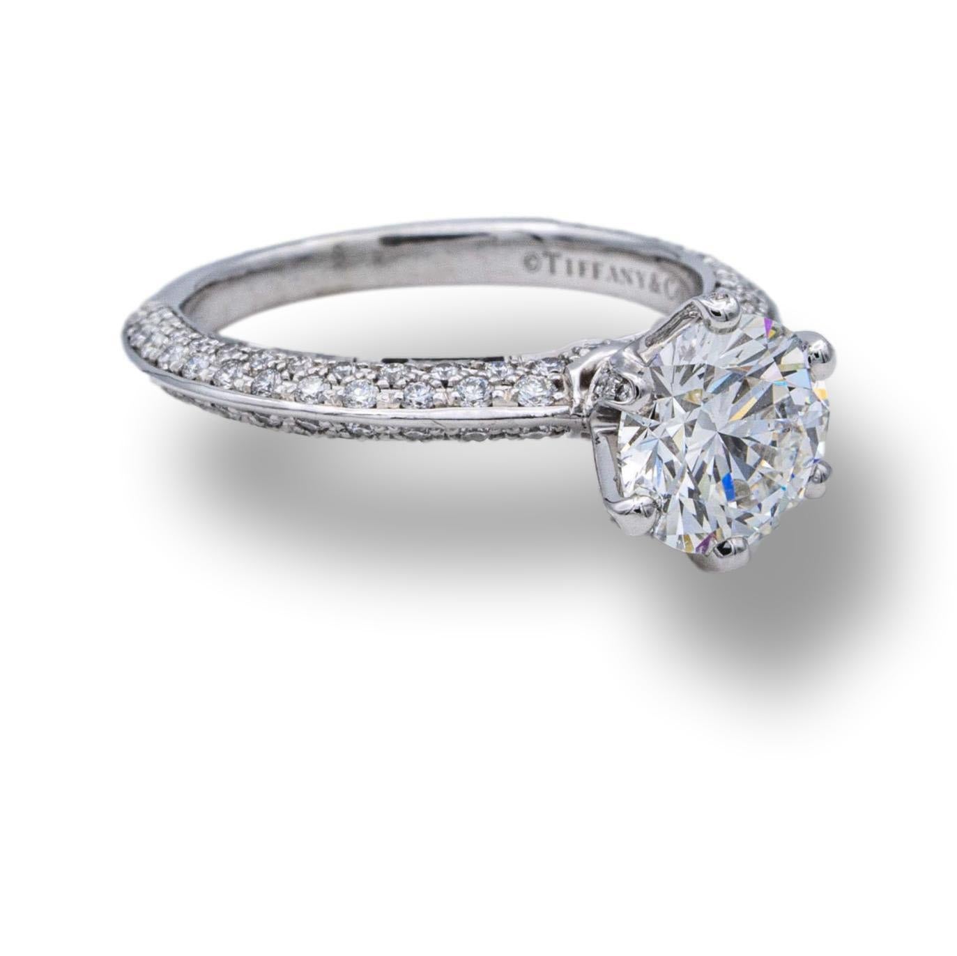 This exquisite Tiffany & Co platinum engagement ring features an excellent cut round diamond weighing 1.02 cts with pave set diamonds weighing 0.37 cts that sparkle brilliantly even in the darkest of corners.

RING SPECIFICATIONS:
Brand: Tiffany &