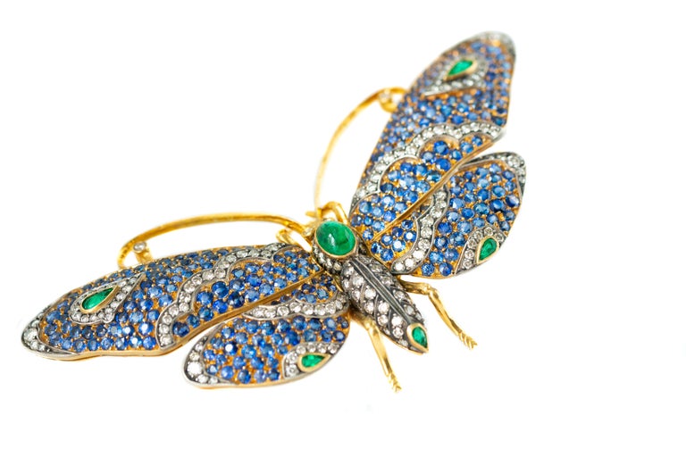 This ornate gorgeous and sparkling gemstone Butterfly Brooch features:
- 15.0 carat total Round Blue Sapphires
- 4.0 carat total Oval and Pear cut Green Emeralds
- 1.5 carat total Round Brilliant Diamonds
- 18 Karat Yellow Gold Brooch with Platinum