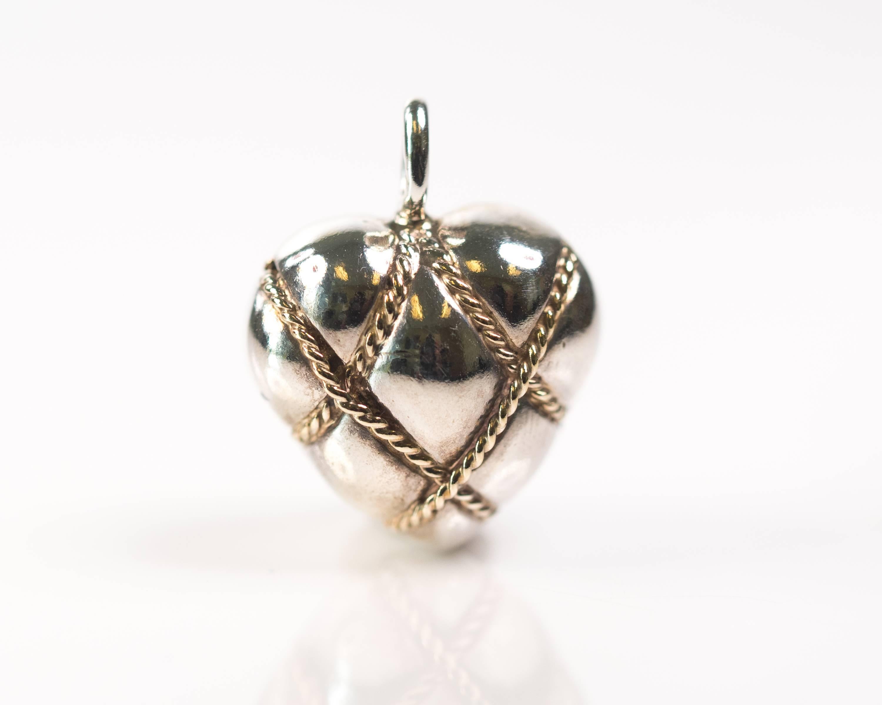Tiffany and Co Quilted Puffed Heart Pendant - Sterling Silver, 14 Karat Yellow Gold

Features a Puffed Sterling Silver heart, 14 Karat Yellow Gold Rope Cable embellishment and a quilted appearance. 
The Gold Rope Cable wraps around the heart in a a