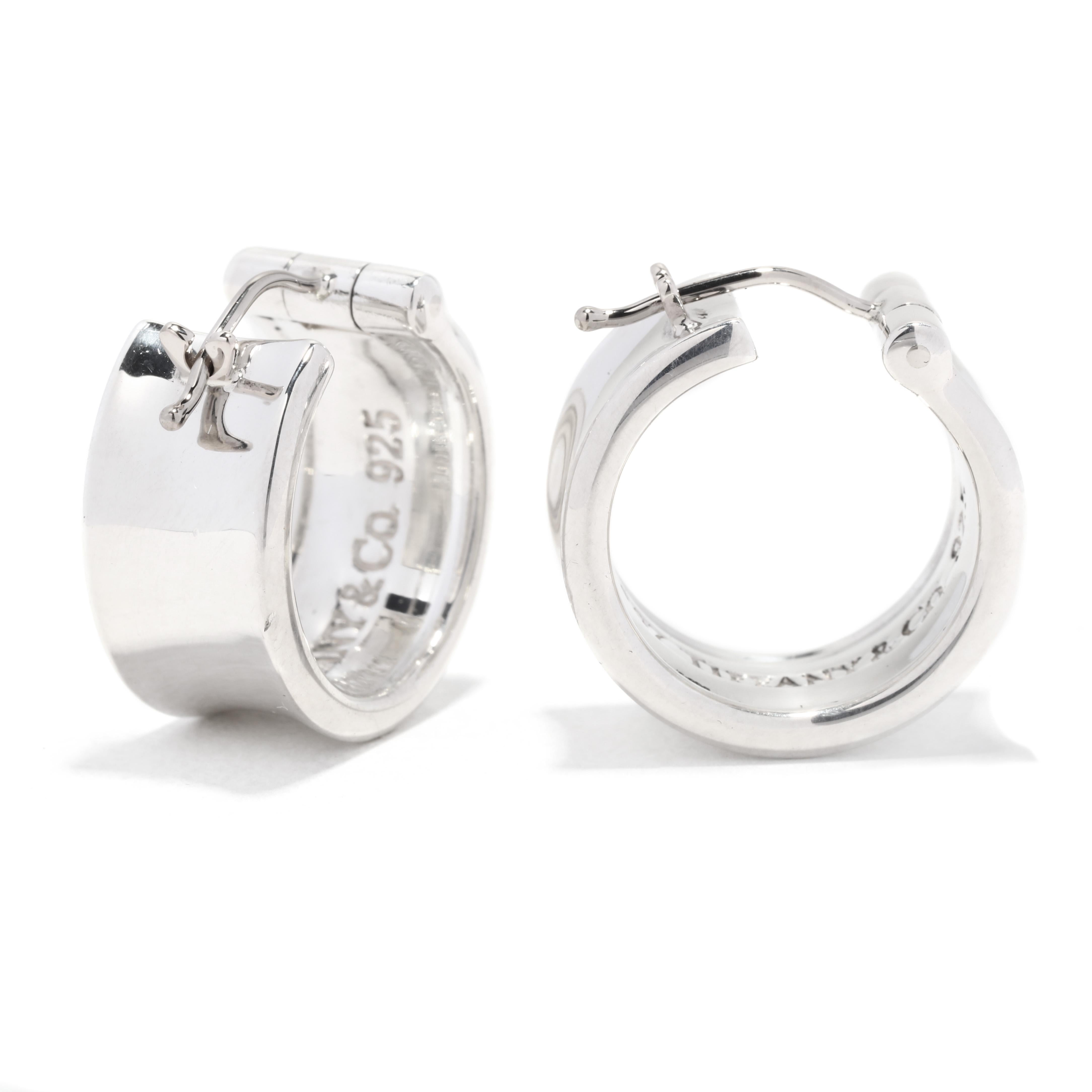 A pair of vintage Tiffany and Company sterling silver wide hoop earrings. These small silver hoops feature a wide, concave design with stamps on the outer edge of 1997, T & Co, and 925.

Length: 3/4 in.

Width: 3/8 in.

Weight: 9.5 dwts. / 14.77