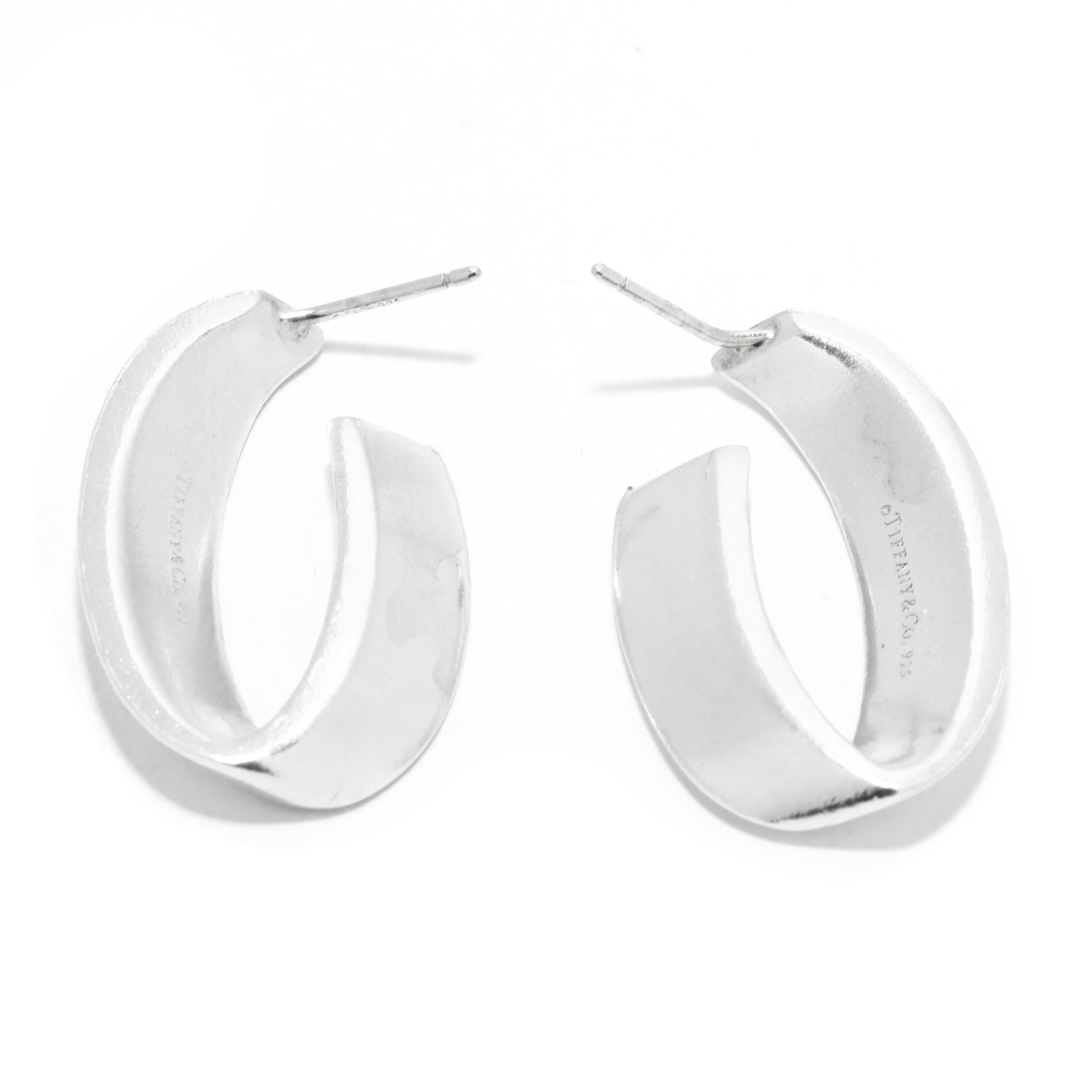 A pair of vintage sterling silver hoop earrings by Tiffany and Company. This everyday hoops feature a flat 'V' shape design with pierced pushbacks.

Length: 1 in.

Width: 5/8 in.

Weight: 4.8 dwts. / 7.5 grams

Stamps: TIFFANY & CO 925

Ring Sizings
