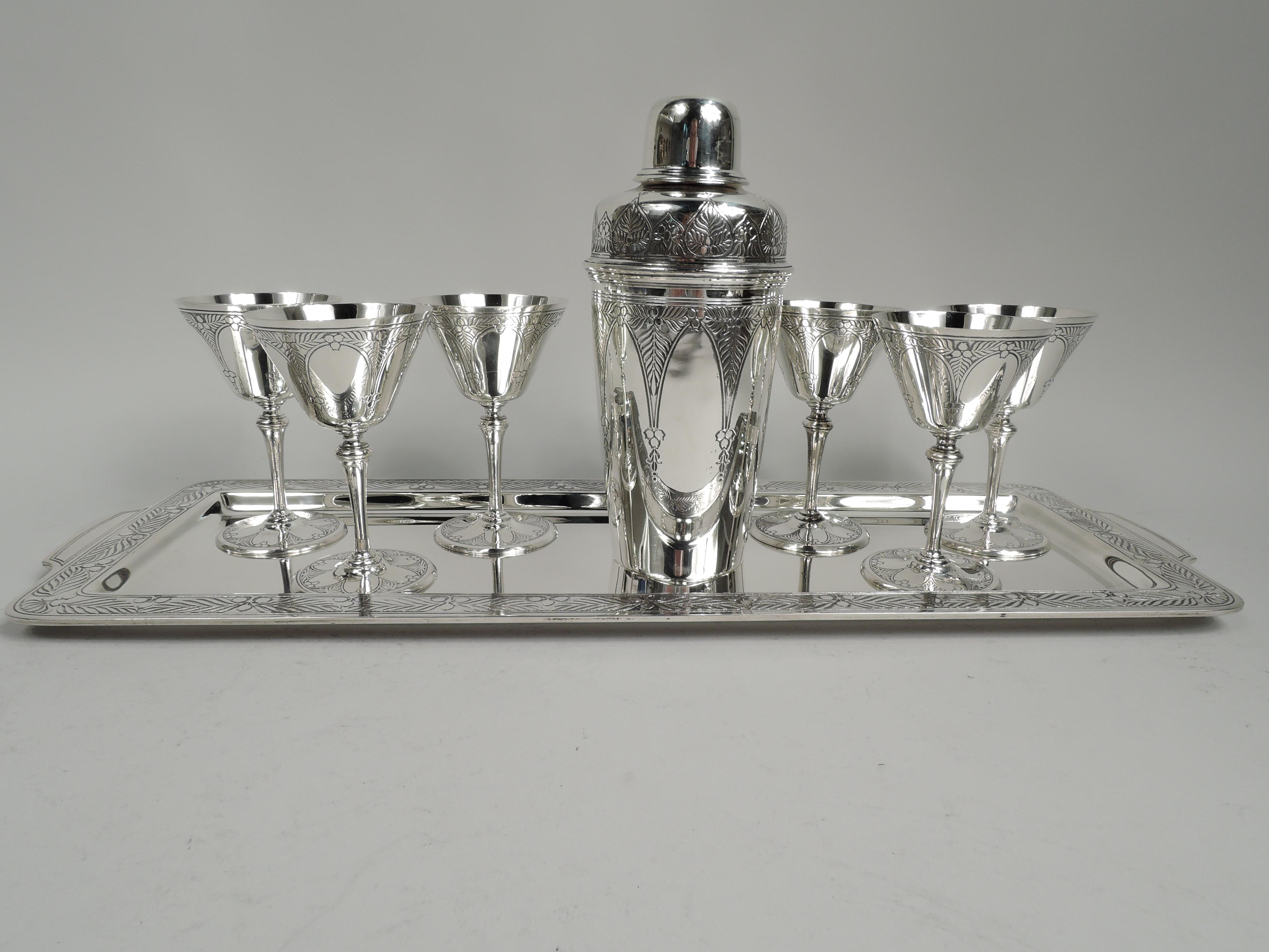 Art Deco sterling silver bar set. Made by Tiffany & Co. in New York, ca 1925. This set comprises cocktail shaker and 6 cups on tray. Shaker: Tapering bowl and detachable top with curved shoulder and short inset neck with tracery-style strainer and