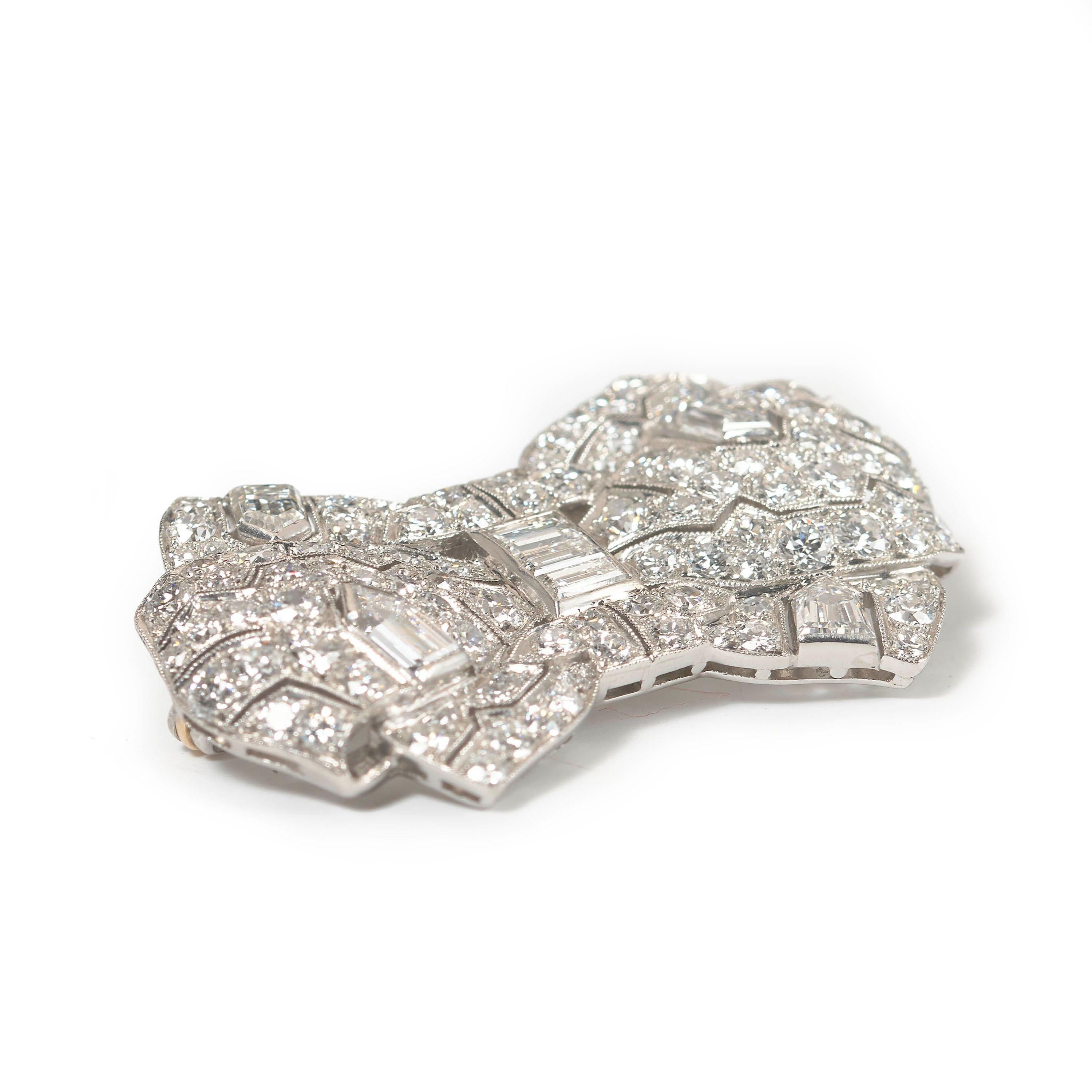 A Tiffany Art Deco diamond and platinum bow brooch, with geometric openwork decoration, set with round brilliant-cut diamonds, in pavé grain settings, baguette and bullet-cut diamonds, in rub over settings, with millegrain edges, mounted in