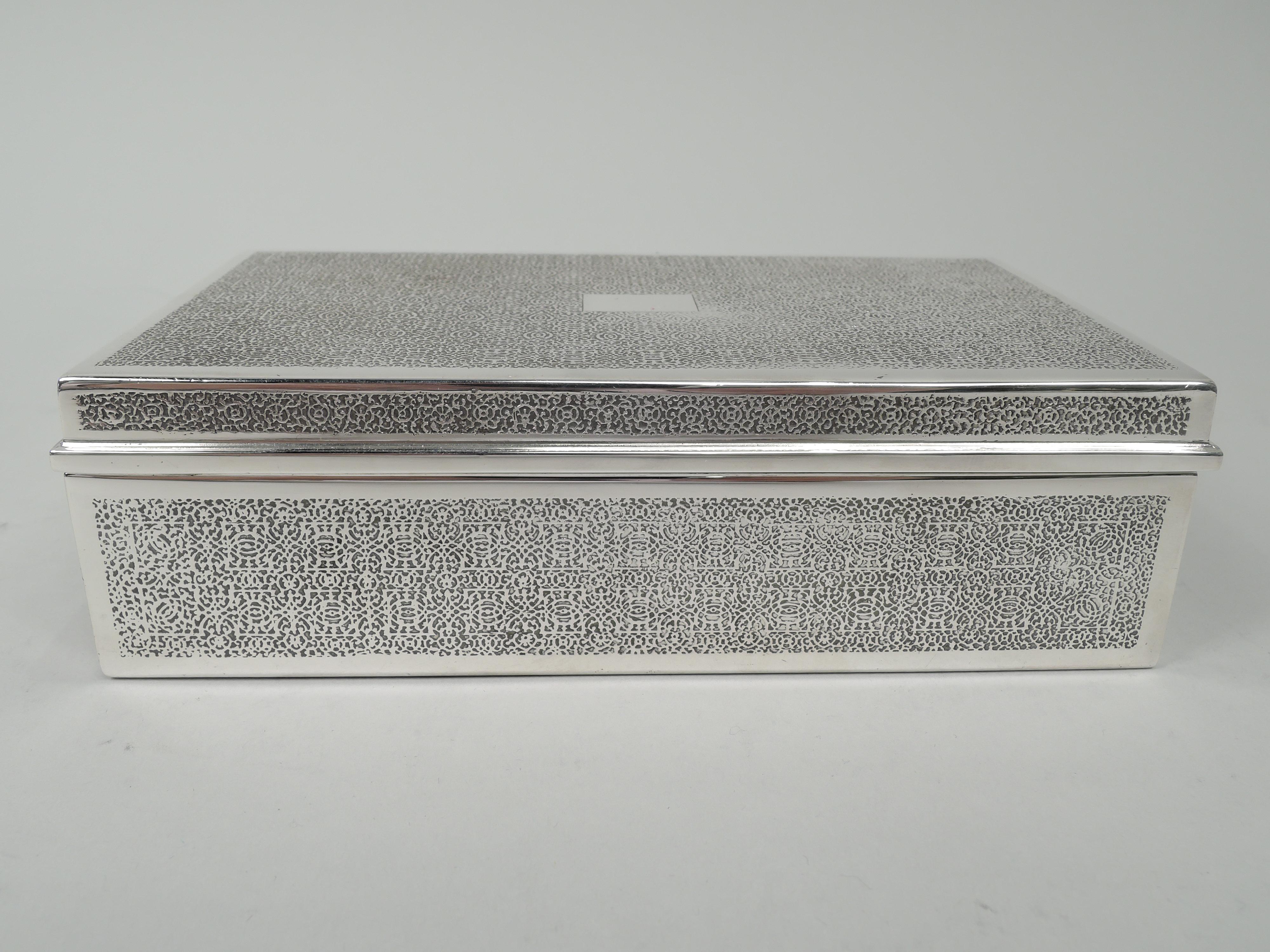 Art Deco sterling silver box. Made by Tiffany & Co. in New York. Rectangular with straights sides and hinged and flat cover. Sides and cover have fine and dense acid-etched allover scrollwork mesh in plain frames. Box interior cedar lined. Cover