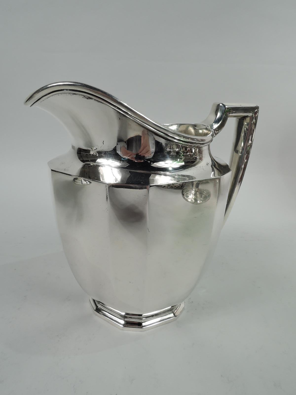 Art Deco sterling silver water pitcher. Made by Tiffany & Co. in New York, ca. 1914. Curved body, stepped foot, helmet mouth, and bracket handle. Alternating wide and narrow facets to body and foot. Fully marked including pattern no. 18799 (first