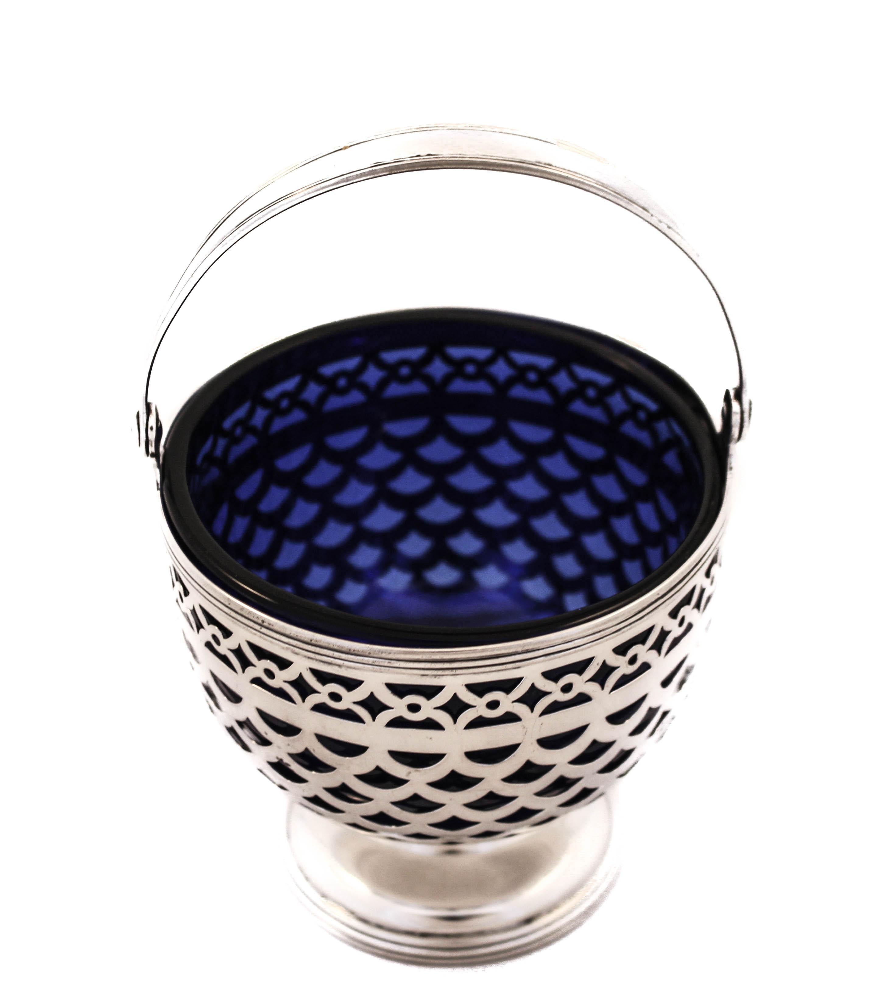 We are proud you this sterling silver bonbon basket with a cobalt glass liner by the world renowned Tiffany and Company. It has a beautiful symmetrical open-work design that allows the cobalt glass to shine through. There is a pedestal in the center
