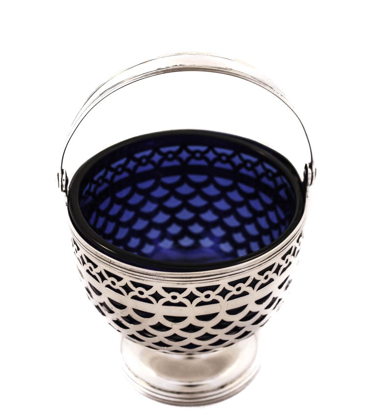 We are proud you this sterling silver bonbon basket with a cobalt glass liner by the world renowned Tiffany and Company. It has a beautiful symmetrical open-work design that allows the cobalt glass to shine through. There is a pedestal in the center