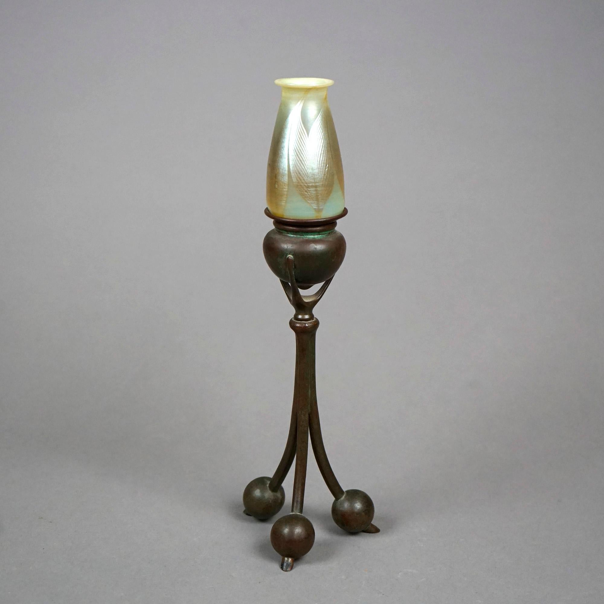 An Arts and Crafts candlestick by Tiffany Studios offers pulled feather art glass shade over cast bronze tripod base, signed on foot as photographed, c1910

Measures- 12.25'' H x 3.5'' W x 3.5'' D.