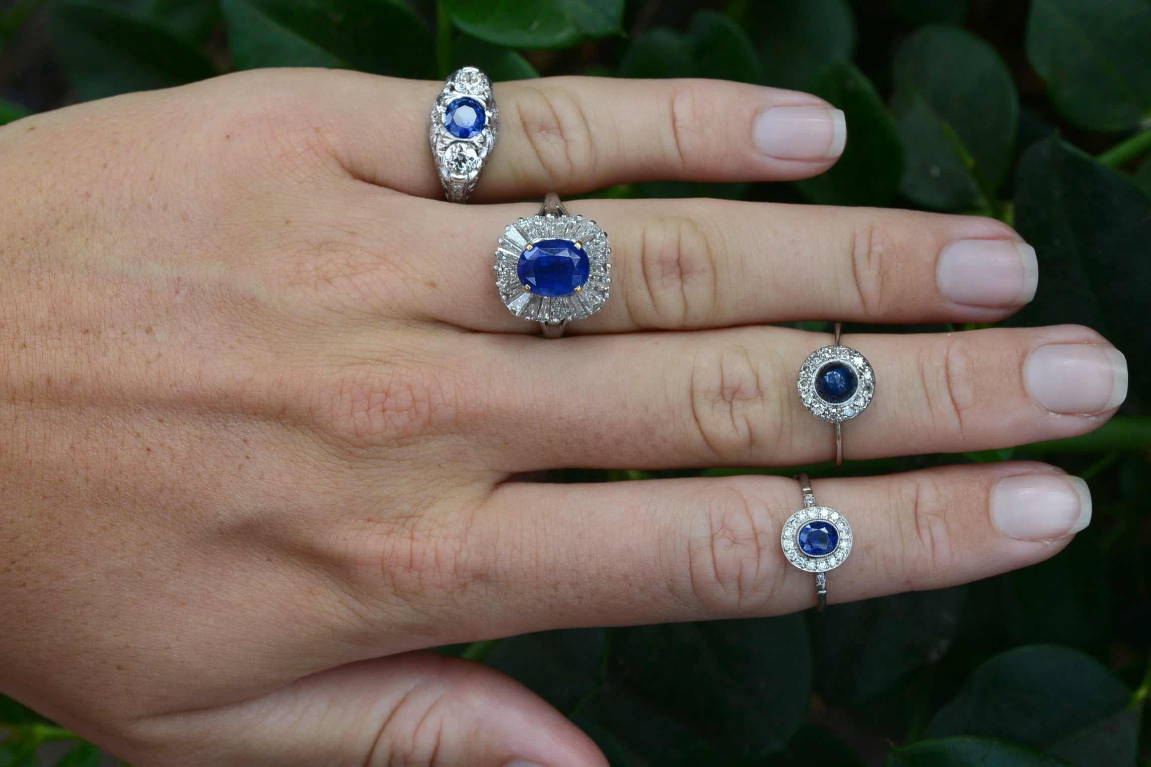 An enticing, original Tiffany Sapphire Cocktail Ring. A natural, unheated sapphire is surrounded by a row of glimmering baguette diamonds, called a Ballerina setting; she resembles a tutu's undulating, wavy edges. The velvety blue of this gemstone