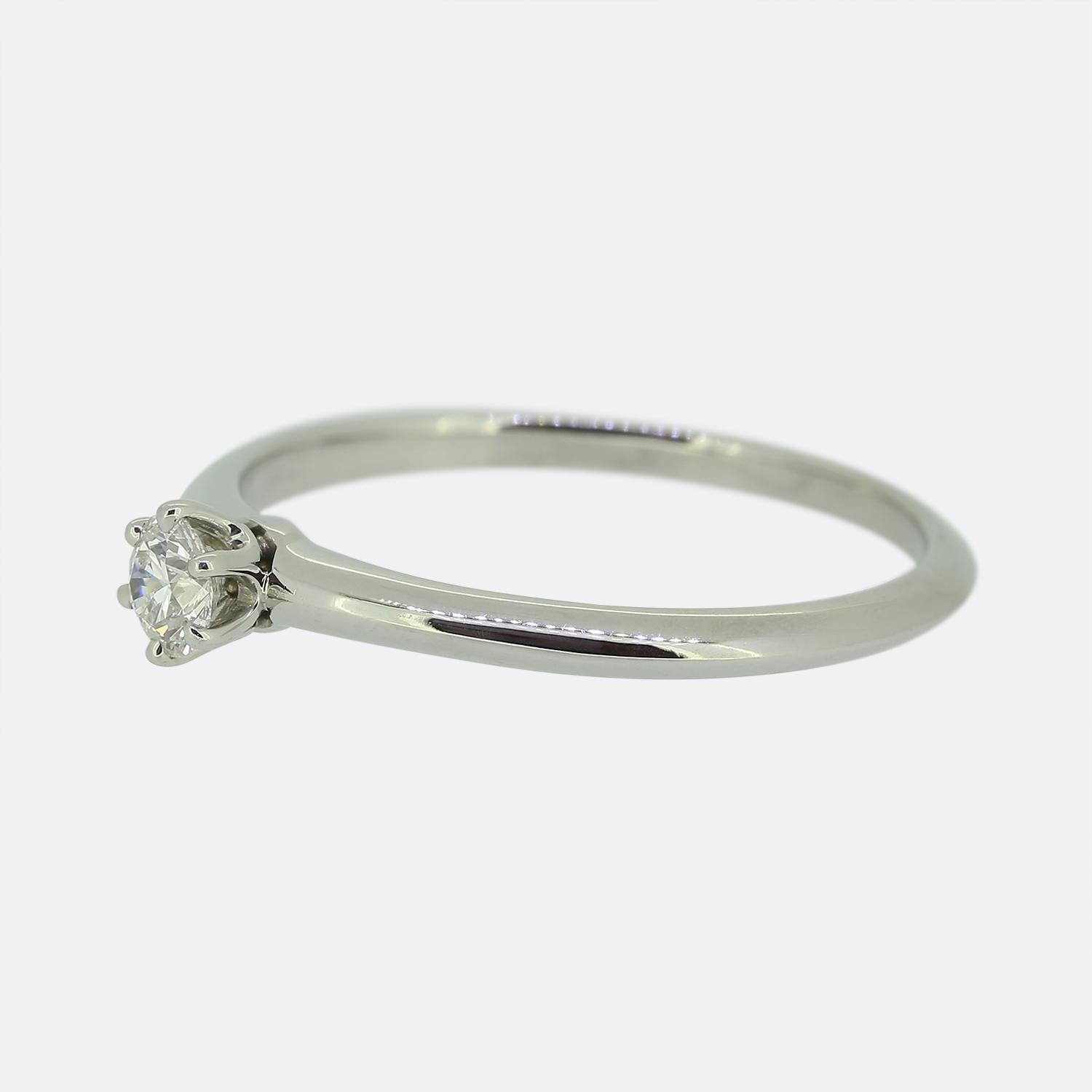 Here we have a classic platinum solitaire engagement ring from the world renowned jewellery designer, Tiffany & Co. At the centre of face we find a single 0.23 carat round brilliant cut diamond which sits alone and proud in 6 clawed setting atop