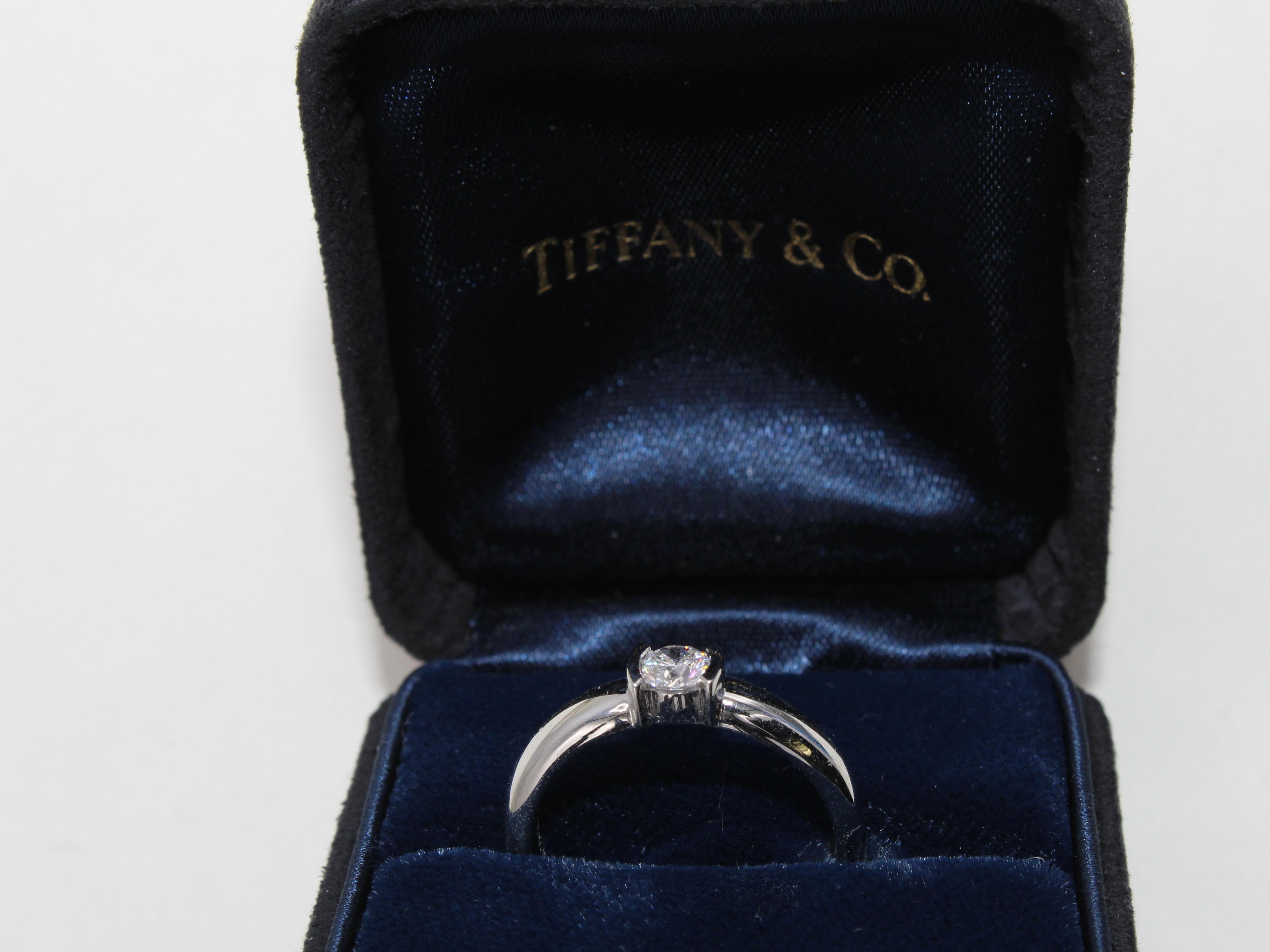 Platinum handcrafted mounting by Tiffany & Co. featuring a perfect round brilliant cut diamond secured by 2 half-moon shaped bezel on either side. A truly contemporary and chic look. The central diamond is accompanied by a Tiffany certificate