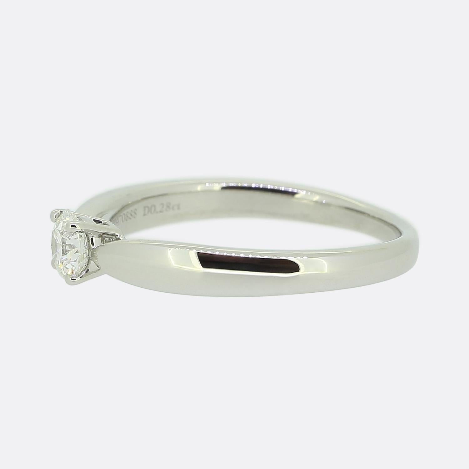 Nous avons ici une magnifique bague solitaire en diamant du créateur de bijoux de renommée mondiale, Tiffany & Co. La pierre centrale est un charmant diamant rond de 0,28 carat taillé en brillant, serti sur l'anneau gradué emblématique de