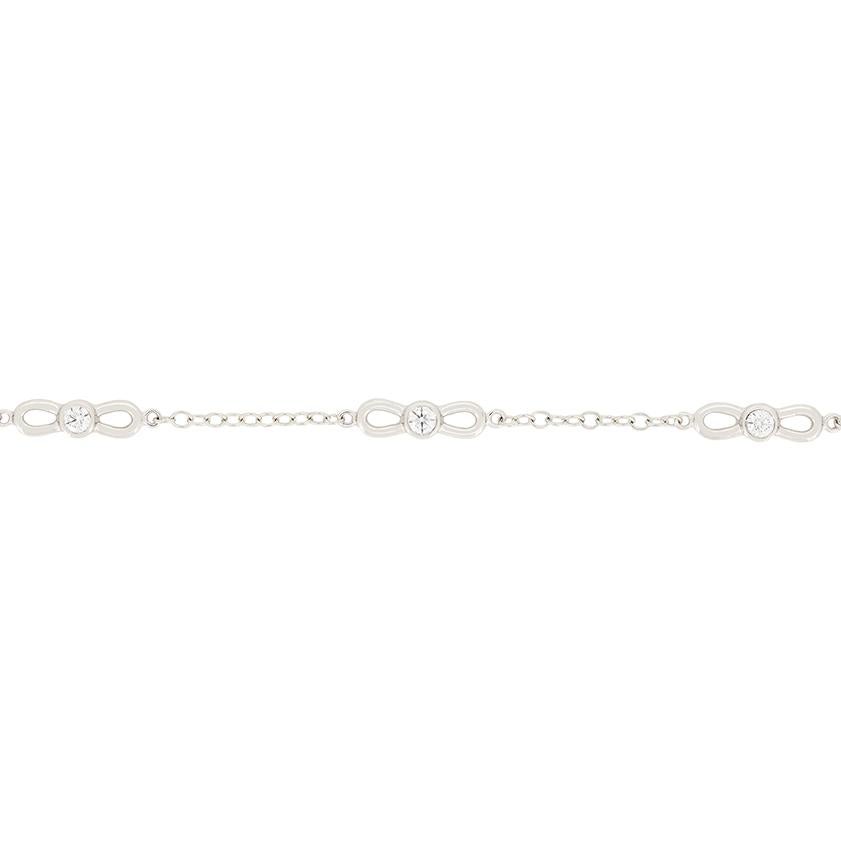 This beautiful bracelet comes from the designer Tiffany & Co. The design centres around five bow motifs, each with a round brilliant diamond rub over set at their centre. The diamonds total 0.30 carat and are of high quality, being graded F in