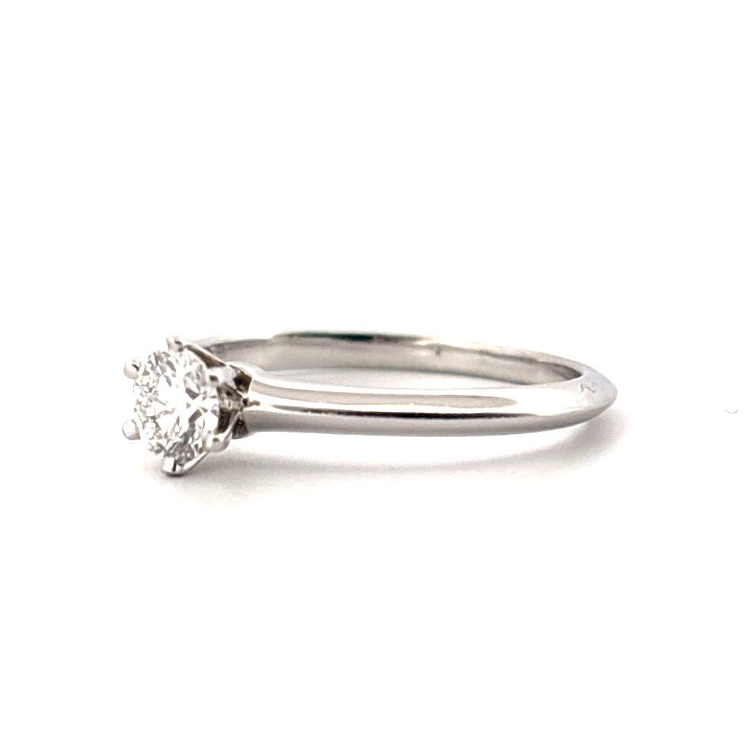 Dieser Solitär-Verlobungsring aus Platin wurde von Tiffany & Co. gefertigt und ist ein zeitloses Symbol für raffinierte Eleganz. Der runde Brillant mit einem Gewicht von 0,31 Karat und den Reinheitsgraden H und VVS1 steht für außergewöhnliche