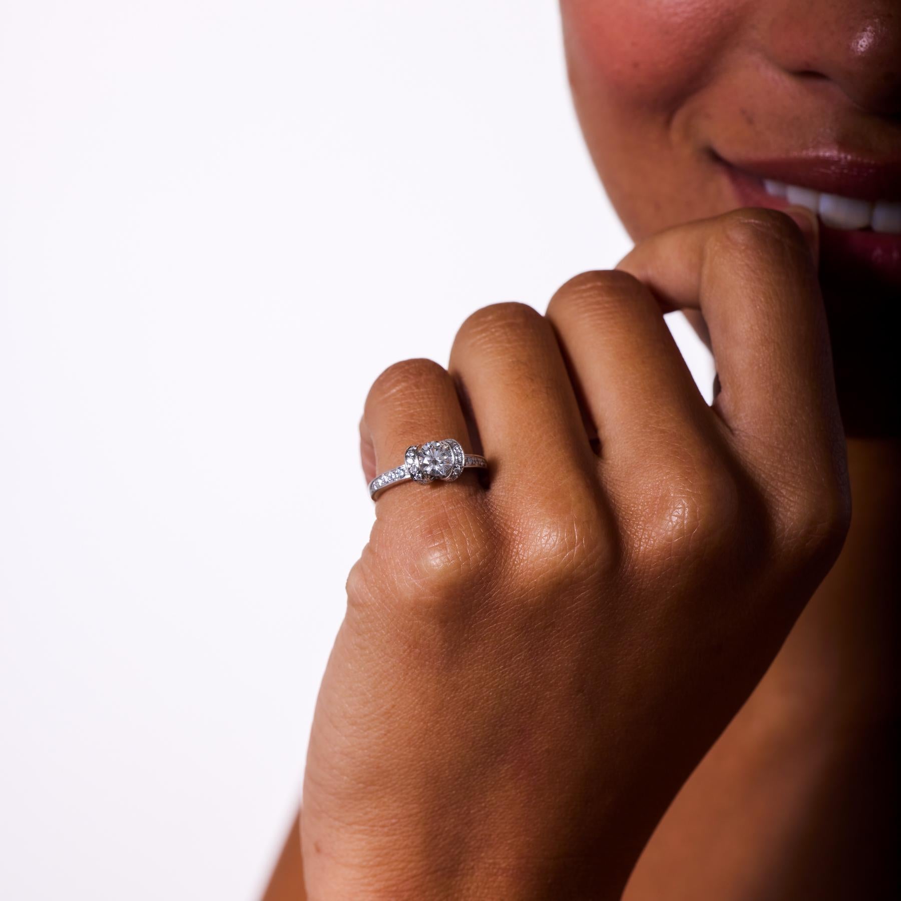 Exquise, cette bague de fiançailles moderne en platine, fabriquée par Tiffany & Co, rayonne de brillance et de grâce intemporelle. Le diamant central de 0,73 carat, de taille ronde et brillante, brille d'une lumière pure, parfaitement complétée par