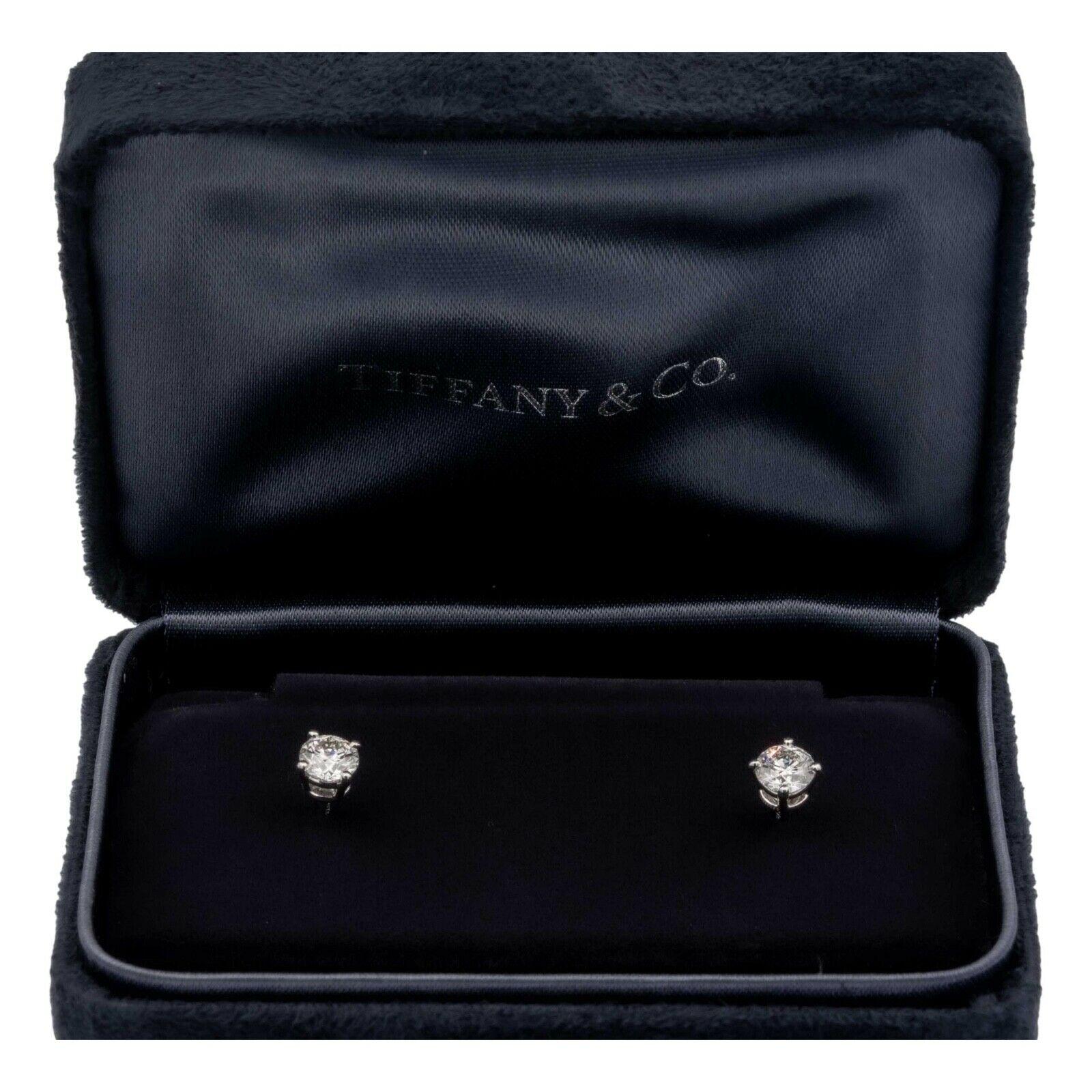 Pair of Tiffany & Co. Diamond Stud earrings finely crafted in a Platinum 4 prong basket setting featuring two perfectly matched round brilliant cut diamonds weighing 0.90 carats total weight. One round brilliant diamond weighs 0.45 carats graded H