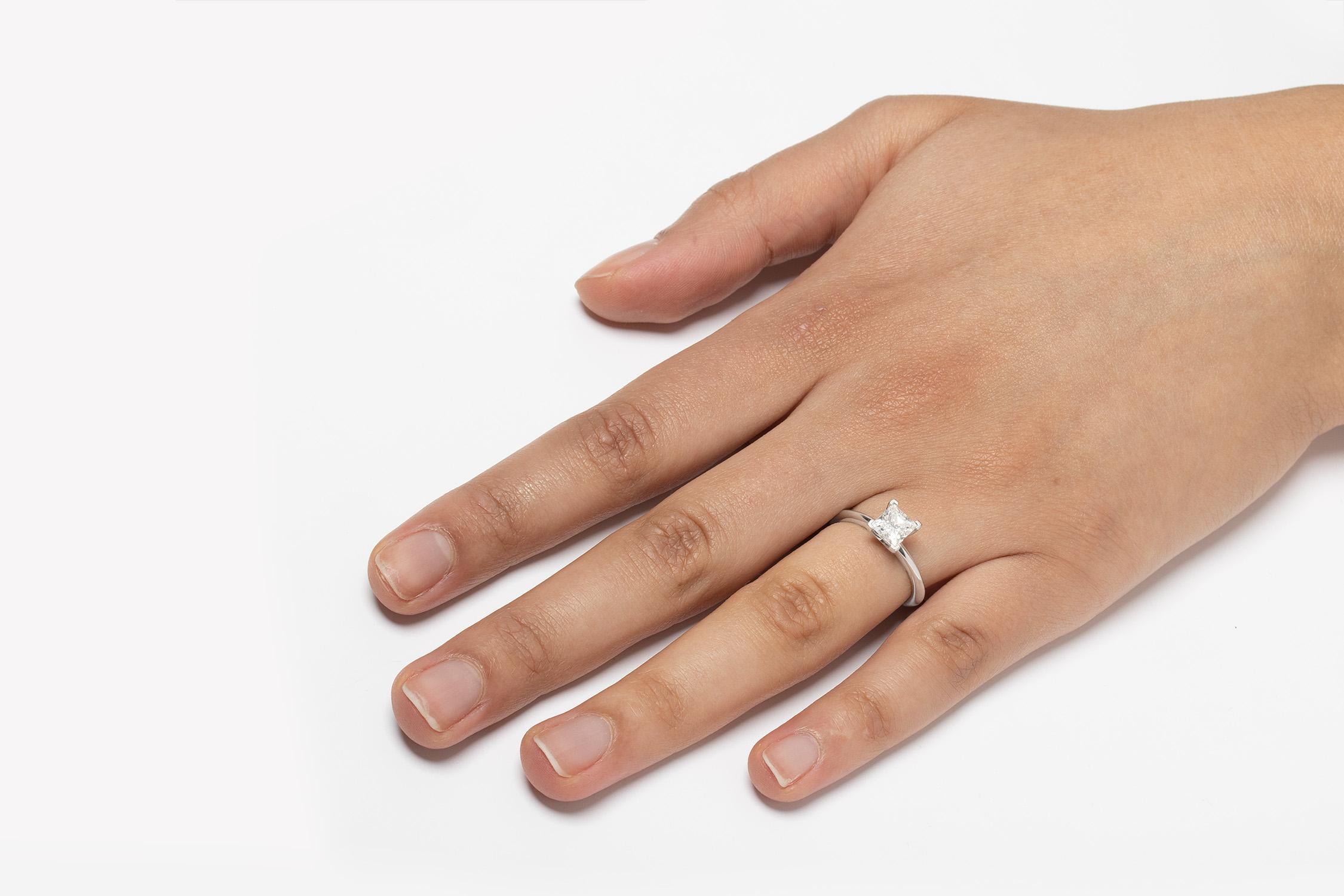 Cette magnifique bague en diamant de Tiffany & Co. présente un diamant de taille princesse dans une monture à quatre griffes. La pierre étincelante pèse 1,01 carat et est certifiée par Tiffany & Co. comme étant de couleur F et de pureté VS1. Il est