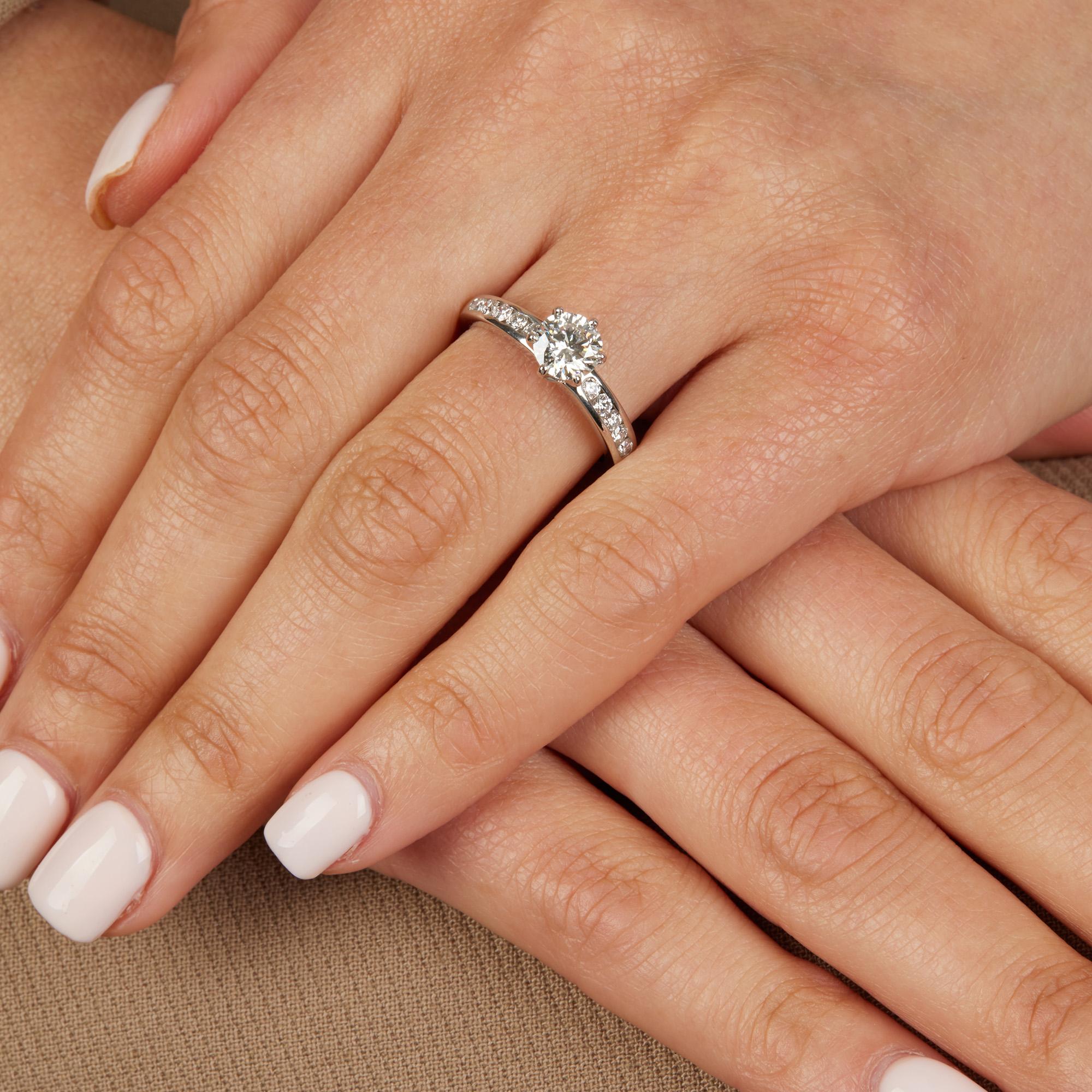 This ring by Tiffany & Co features their signature Tiffany setting and has a 1.03ct round brilliant cut diamond at its centre complemented by a half diamond band set in platinum. Accompanied by a Tiffany ring box. 
ITEM