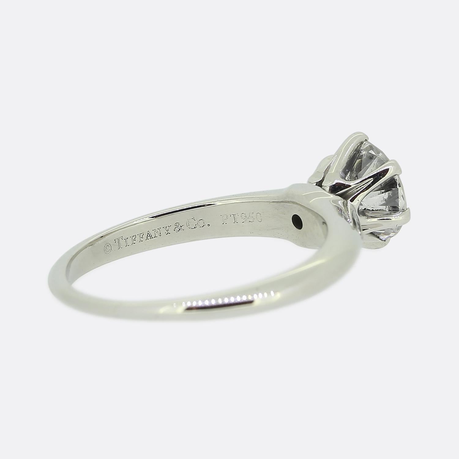 Nous avons ici une magnifique bague de fiançailles solitaire du créateur de bijoux de renommée mondiale, Tiffany & Co. La pierre centrale est un magnifique diamant rond de 1,05 carat taillé en brillant, serti dans une monture emblématique de Tiffany