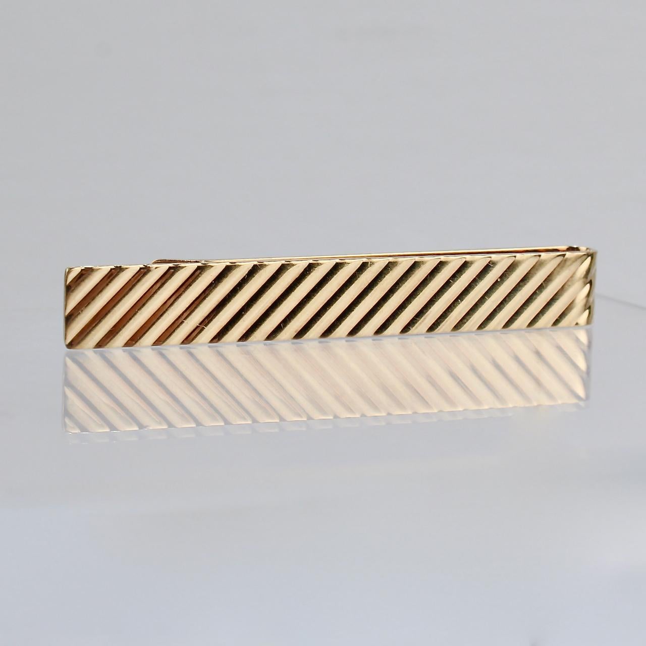 A handsome Tiffany & Co. tie clip in 14K gold.

The tie bar features a repeating diagonal stripe pattern. 

Simple and elegant design from Tiffany!

Date:
Mid-20th Century

Overall Condition:
It is in overall good, as-pictured, used estate condition