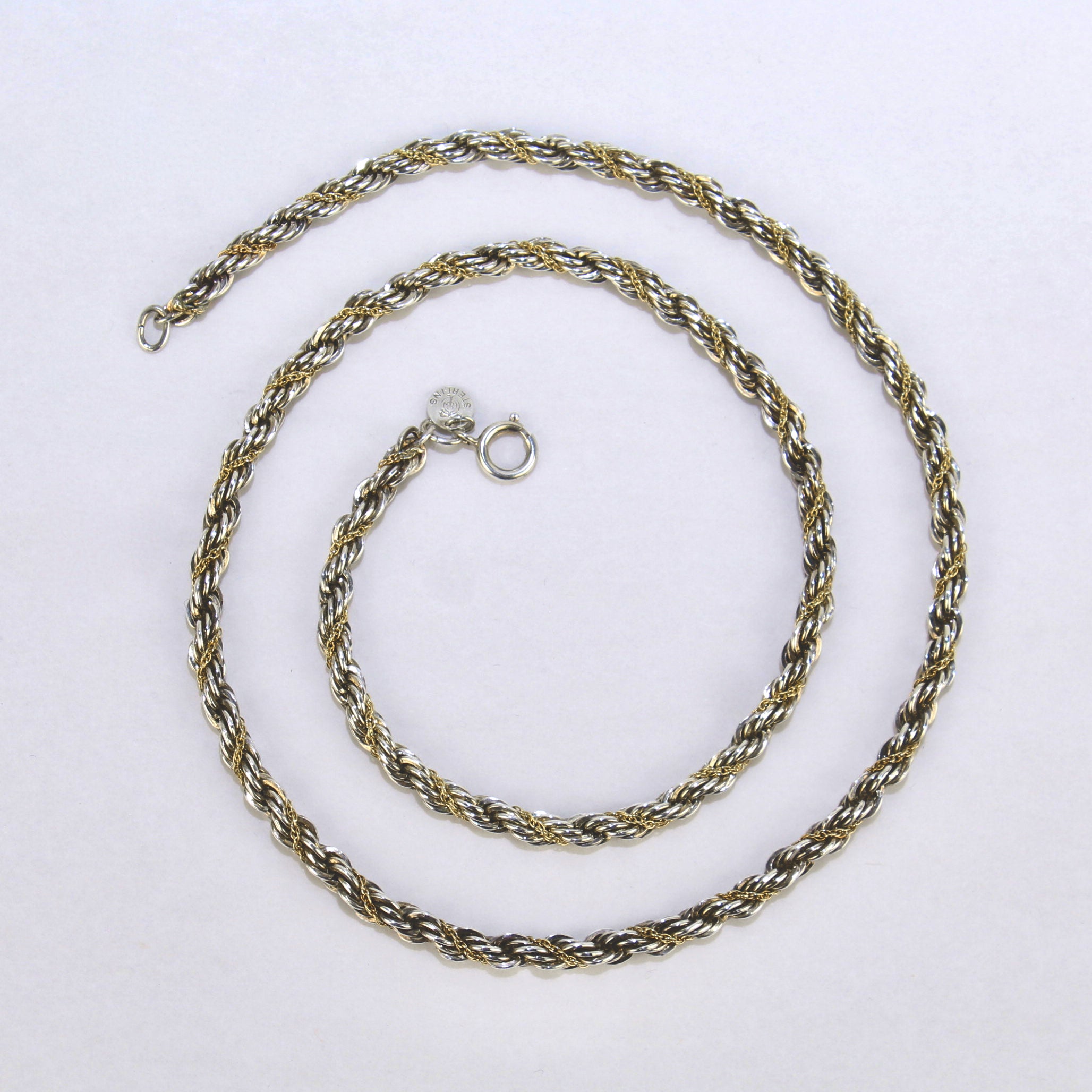 A very fine Tiffany & Co. 14k gold and sterling silver rope twist necklace.

Comprised of a long 24-inch sterling silver rope-link necklace with twisted 14k gold cable chain wrapped in between the silver link pattern. 

Simply a wonderful Tiffany